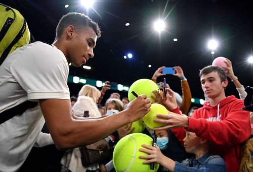 Felix Auger-Aliassime signs tennis balls for fans at the 2021 Rolex Paris Masters