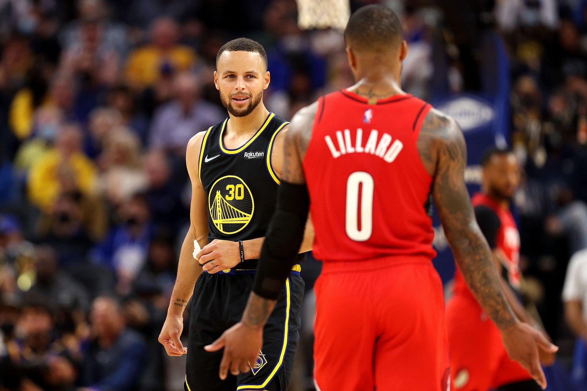 Steph Curry #30 of the Golden State Warriors talks with Damian Lillard #0 of the Portland Trail Blazers during the first half of the game at Chase Center on November 26, 2021 in San Francisco, California.