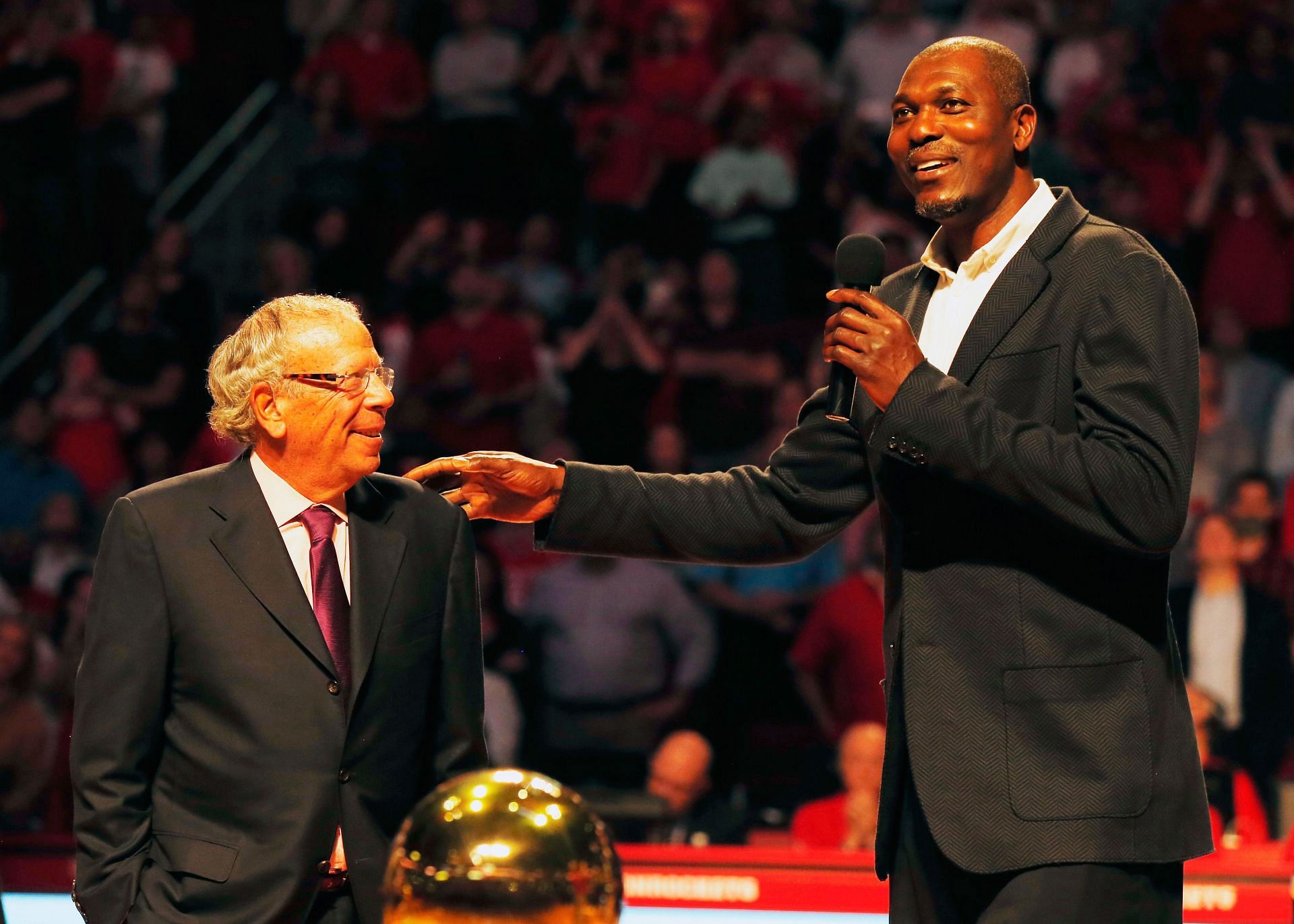 Fomer Houston Rocket Hakeem Olajuwon speaks to the crowd alongside team owner Leslie Alexander as the team honors the 20th anniversary of back-to-back NBA championships at halftime of their game against the Denver Nuggets on March 19, 2015, in Houston.