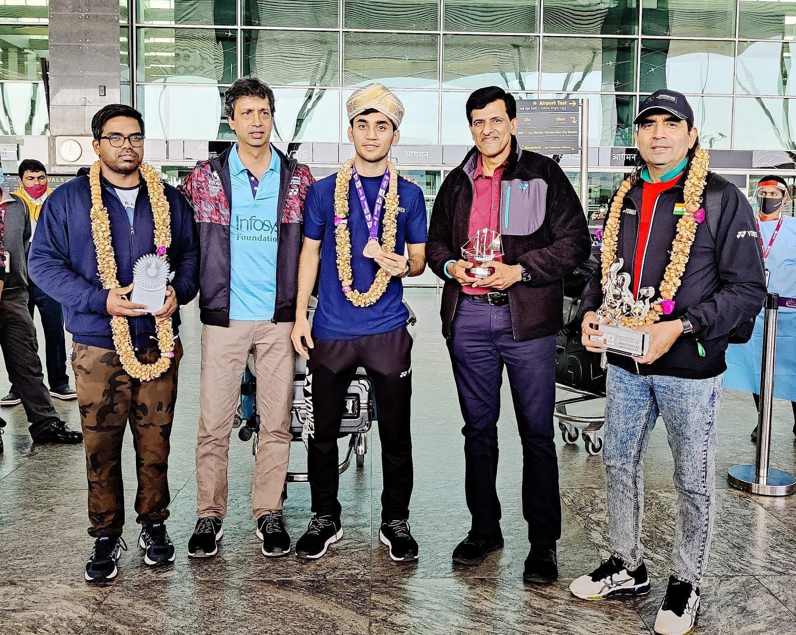 Lakshya Sen (C) was given a warm welcome by Vimal Kumar (2nd from R) at the Bengaluru Airport on Tuesday. Physio Abdul Wahid (extreme left) and DK Sen (extreme right) are also seen in the picture. (Image courtesy: DK Sen)