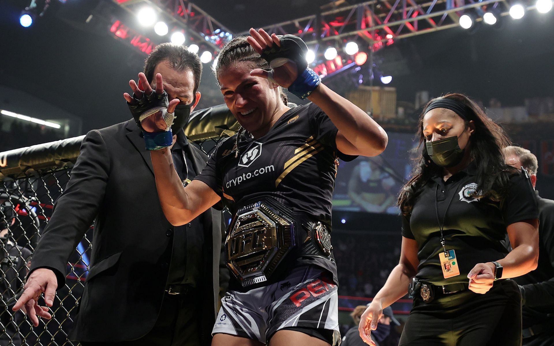Julianna Pena (center) exits the octagon in a Crypto.com kit following her victory over Amanda Nunes
