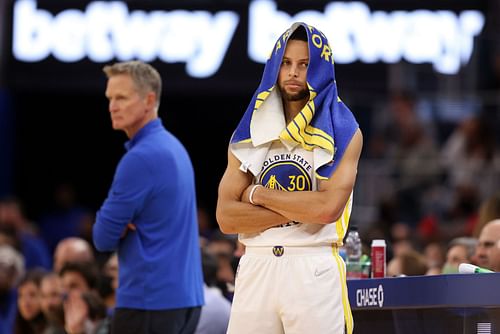 Steve Kerr and Steph Curry watch on during a game