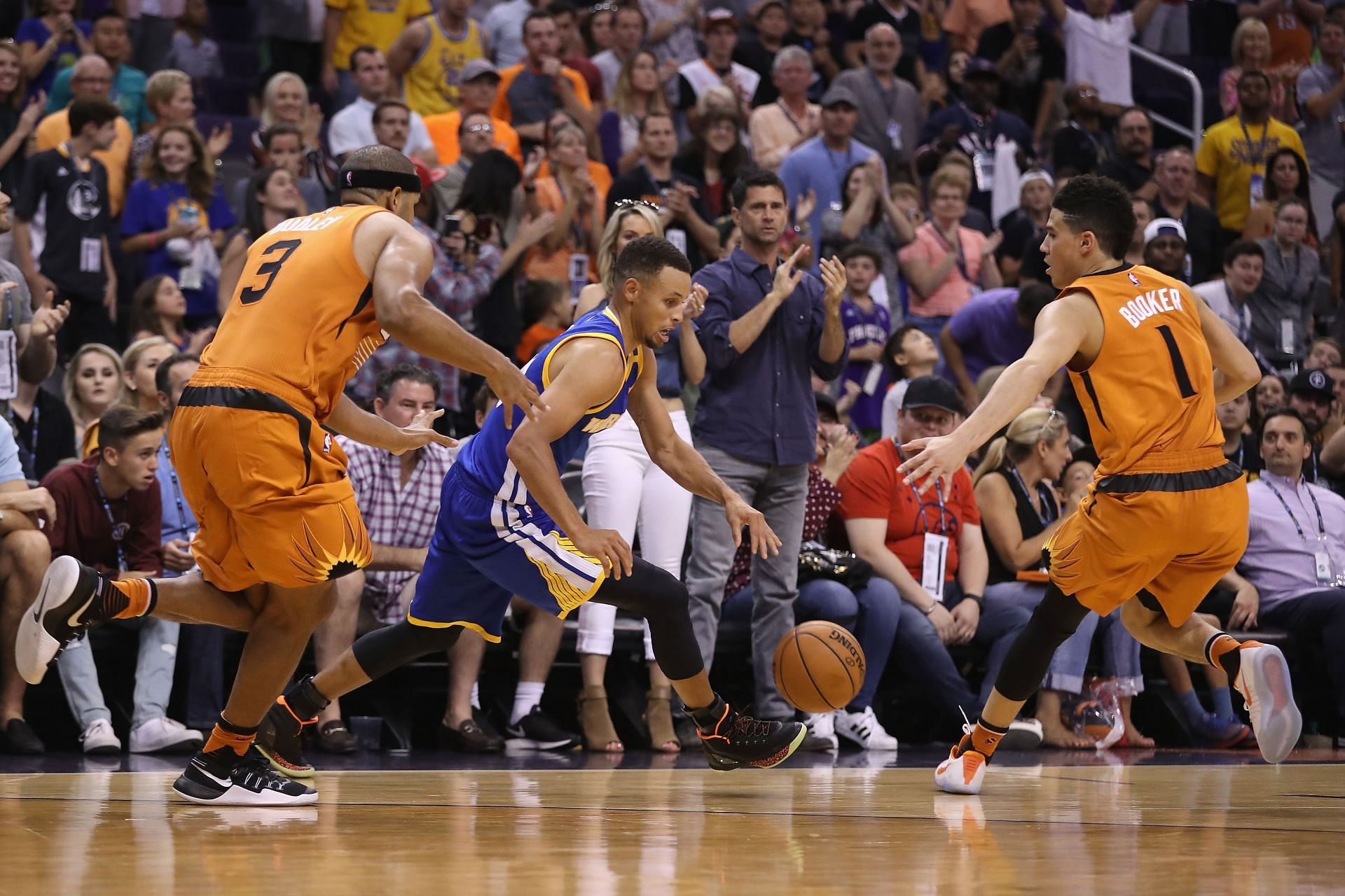 Golden State Warriors Stephen Curry with the ball and Phoenix Suns Devin Booker #1 trying to guard him