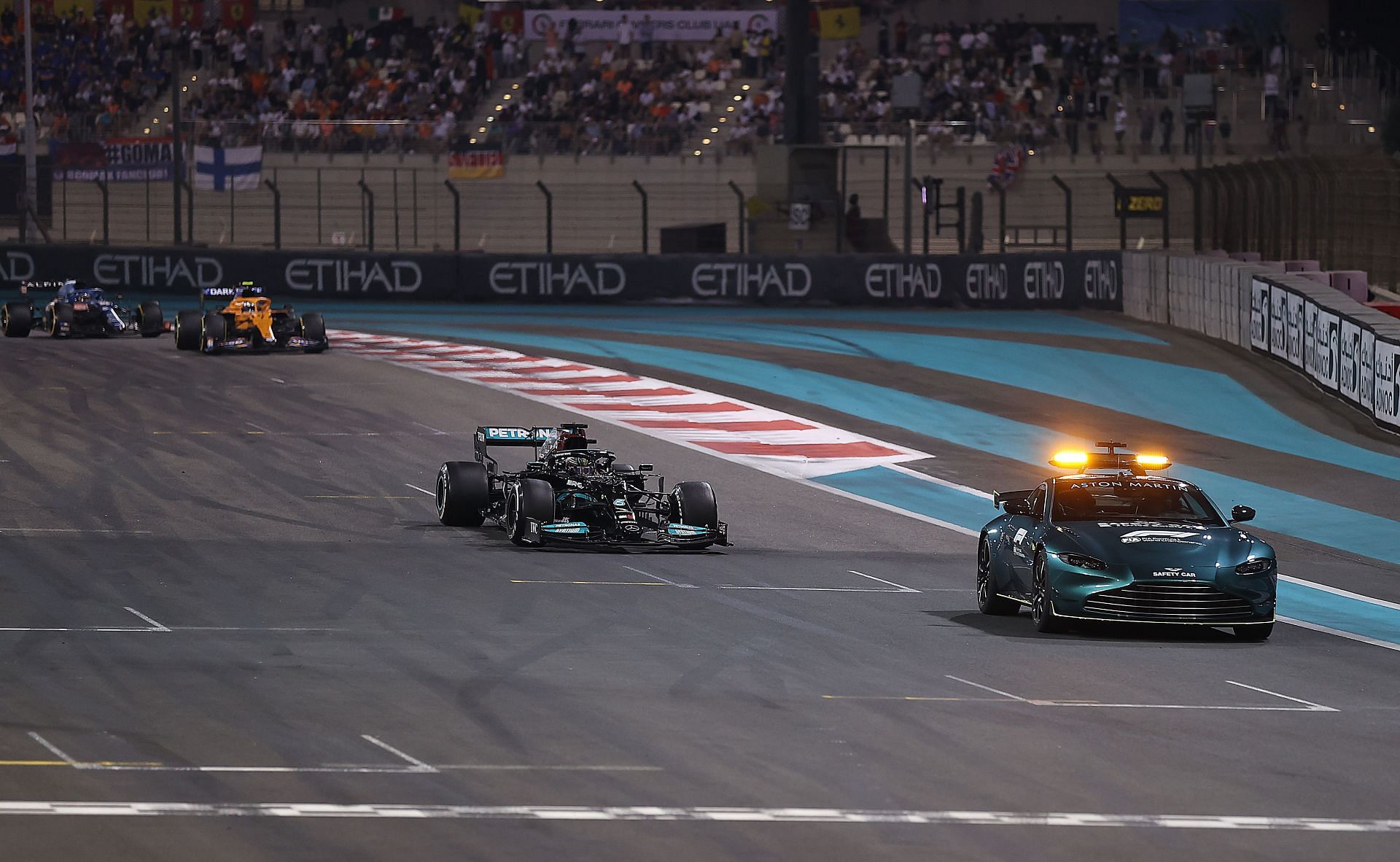 FIA Safety car (right) leads Lewis Hamilton&#039;s Mercedes (centre), with the rest of grid in the background, on lap 55 of the Abu Dhabi Grand Prix