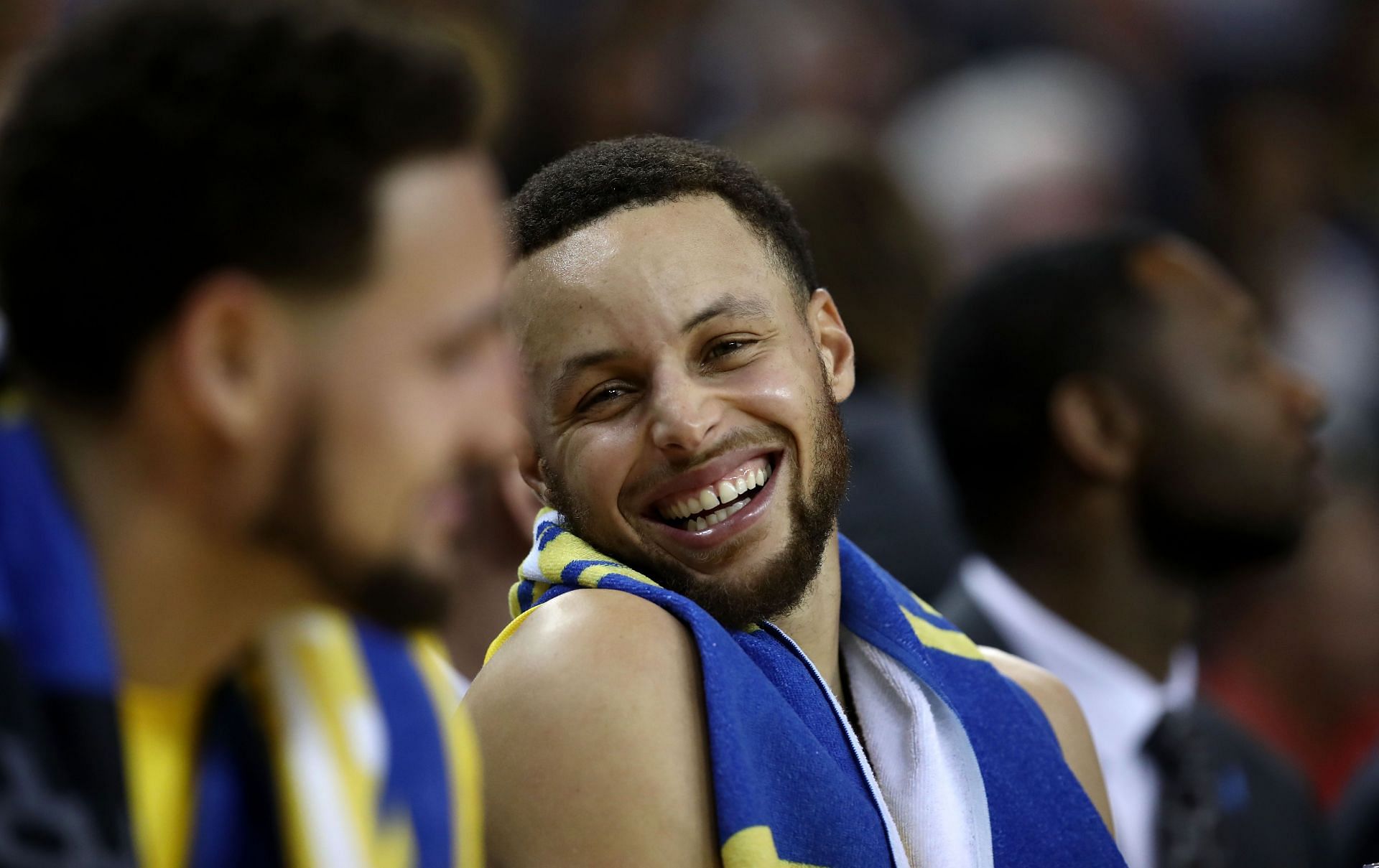 Stephen Curry #30 of the Golden State Warriors smiles as he talks to Klay Thompson #11 on the bench in the final minutes of their game against the Denver Nuggets at ORACLE Arena on April 02, 2019 in Oakland, California.