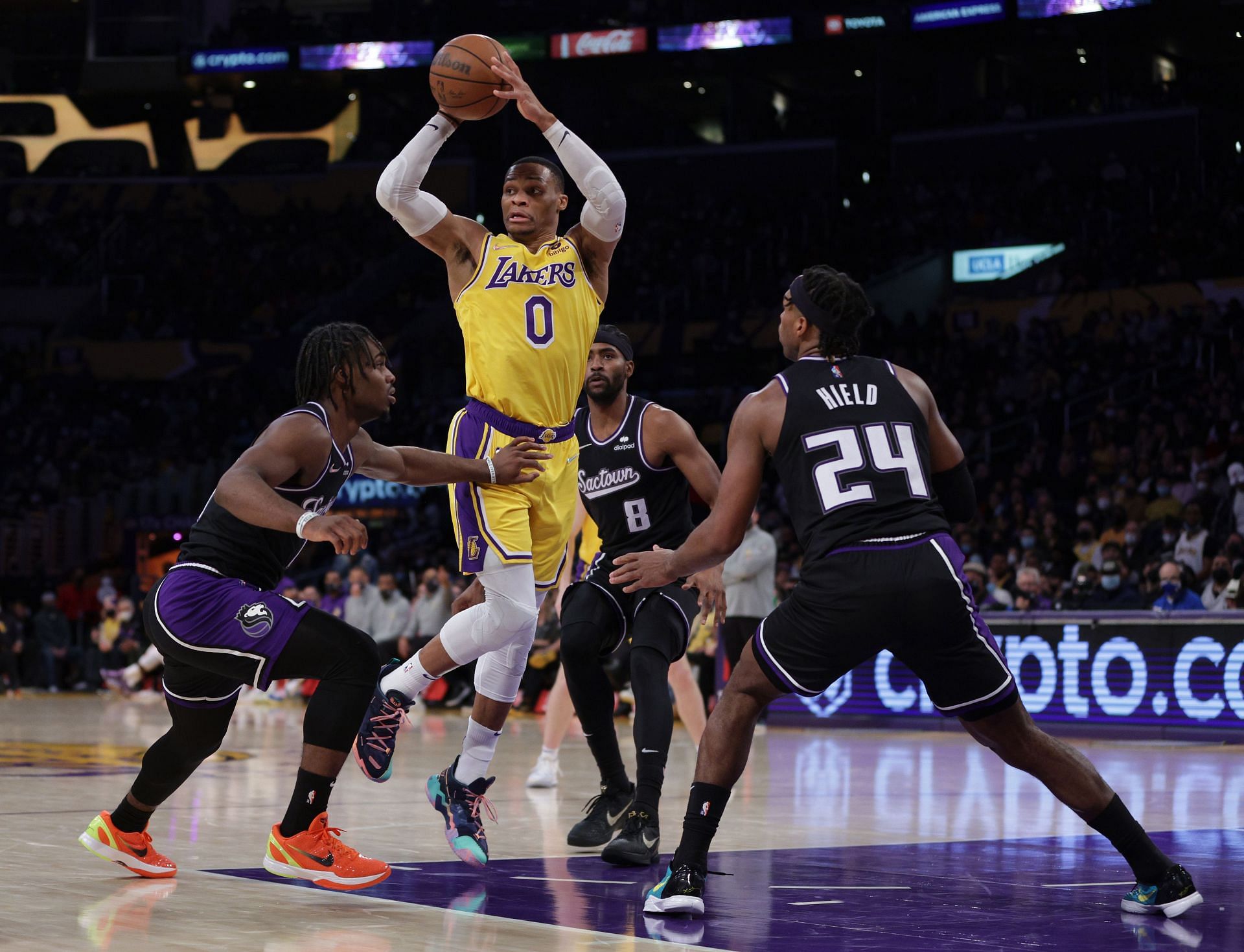 Russell Westbrook of the LA Lakers passes between Davion Mitchell, left, Maurice Harkless (8) and Buddy Hield (24) of the Sacramento Kings.