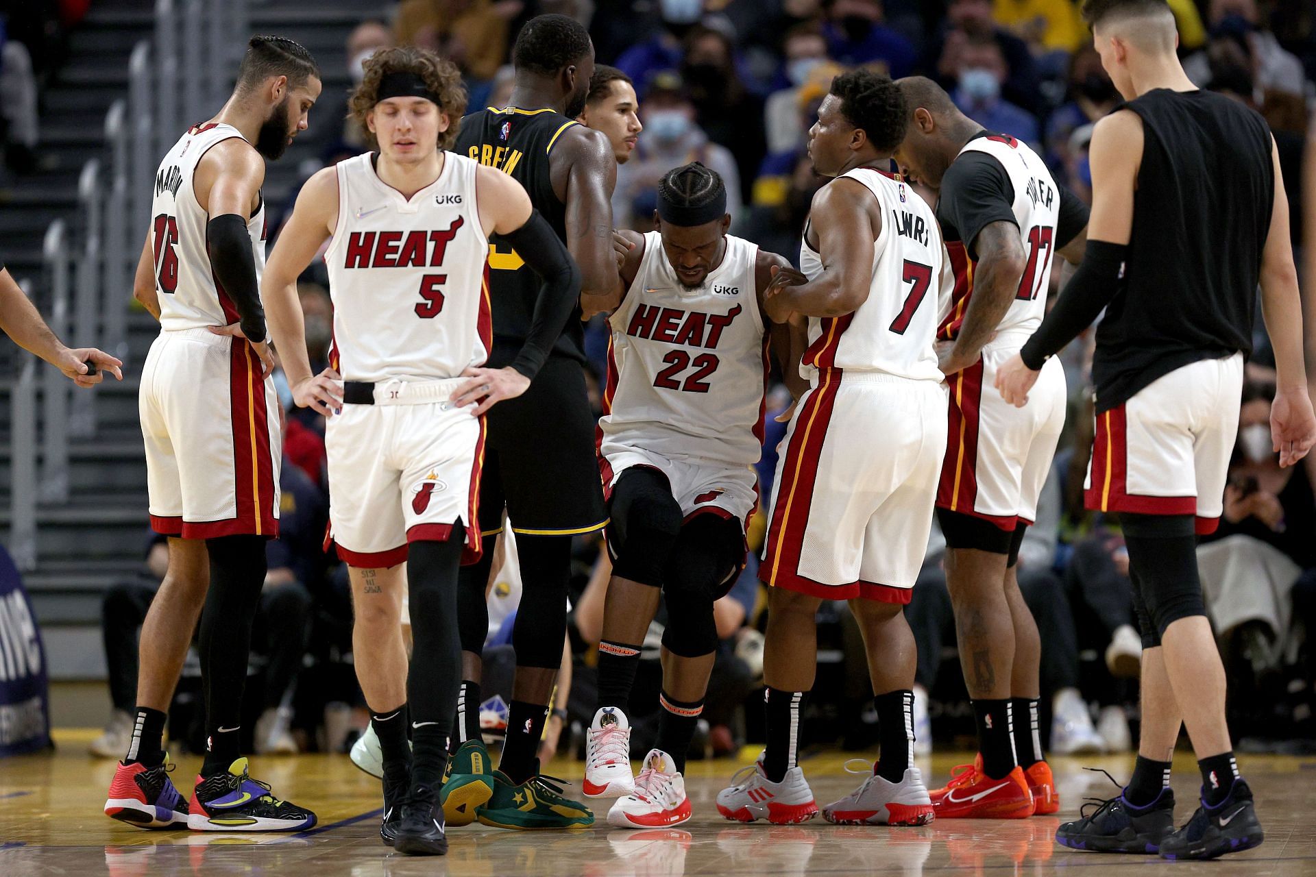 Jimmy Butler of the Miami Heat gets helped up by his teammates after suffering an ankle injury