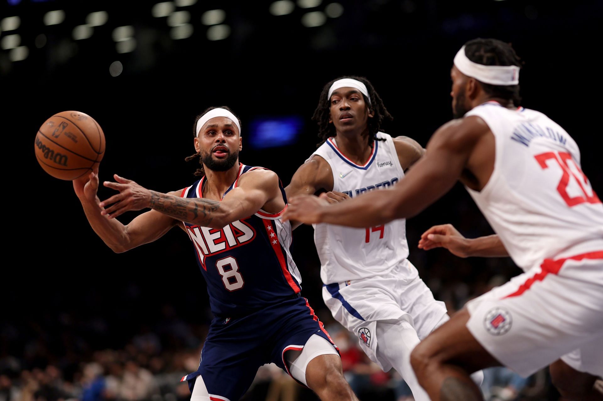 Patty Mills #8 of the Brooklyn Nets passes the ball defended by Justice Winslow #20 of the Los Angeles Clippers and Terance Mann #14 of the Los Angeles Clippers during the fourth quarter at Barclays Center on January 01, 2022 in New York City.