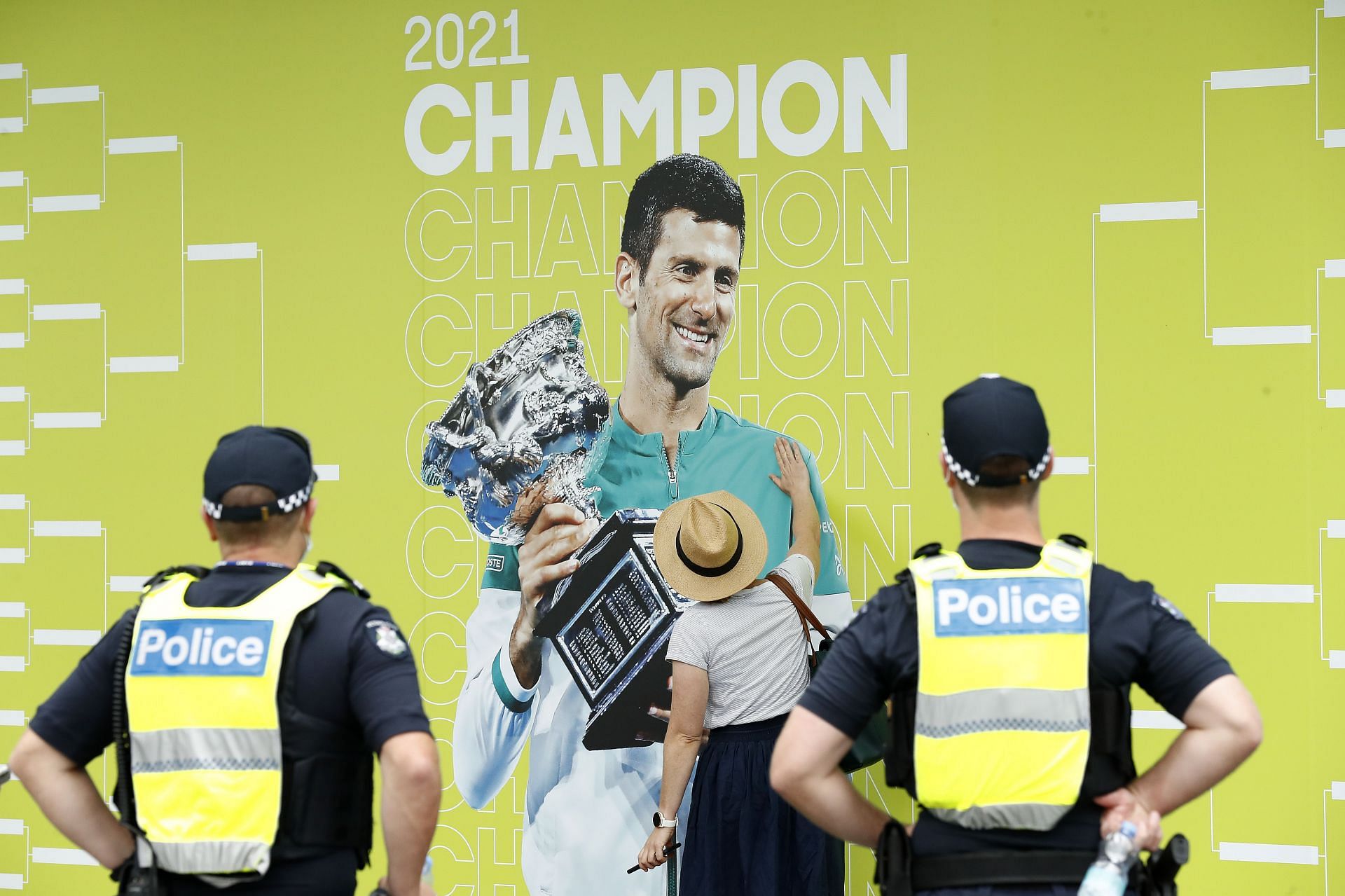 A spectator touches a banner of 2021 Australian Open winner Novak Djokovic at the 2022 Australian Open in Melbourne, Australia