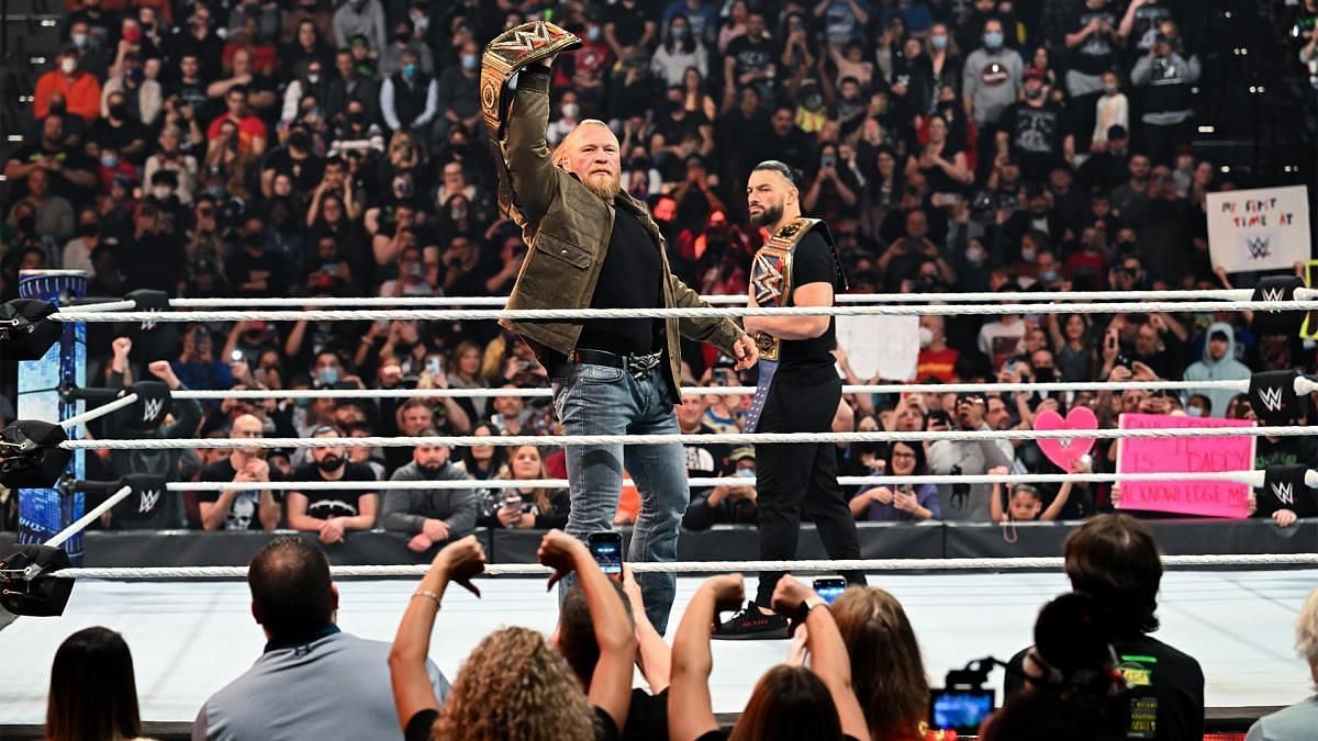 WWE Champion Brock Lesnar shows off his title as Universal Champion Roman Reigns watches on