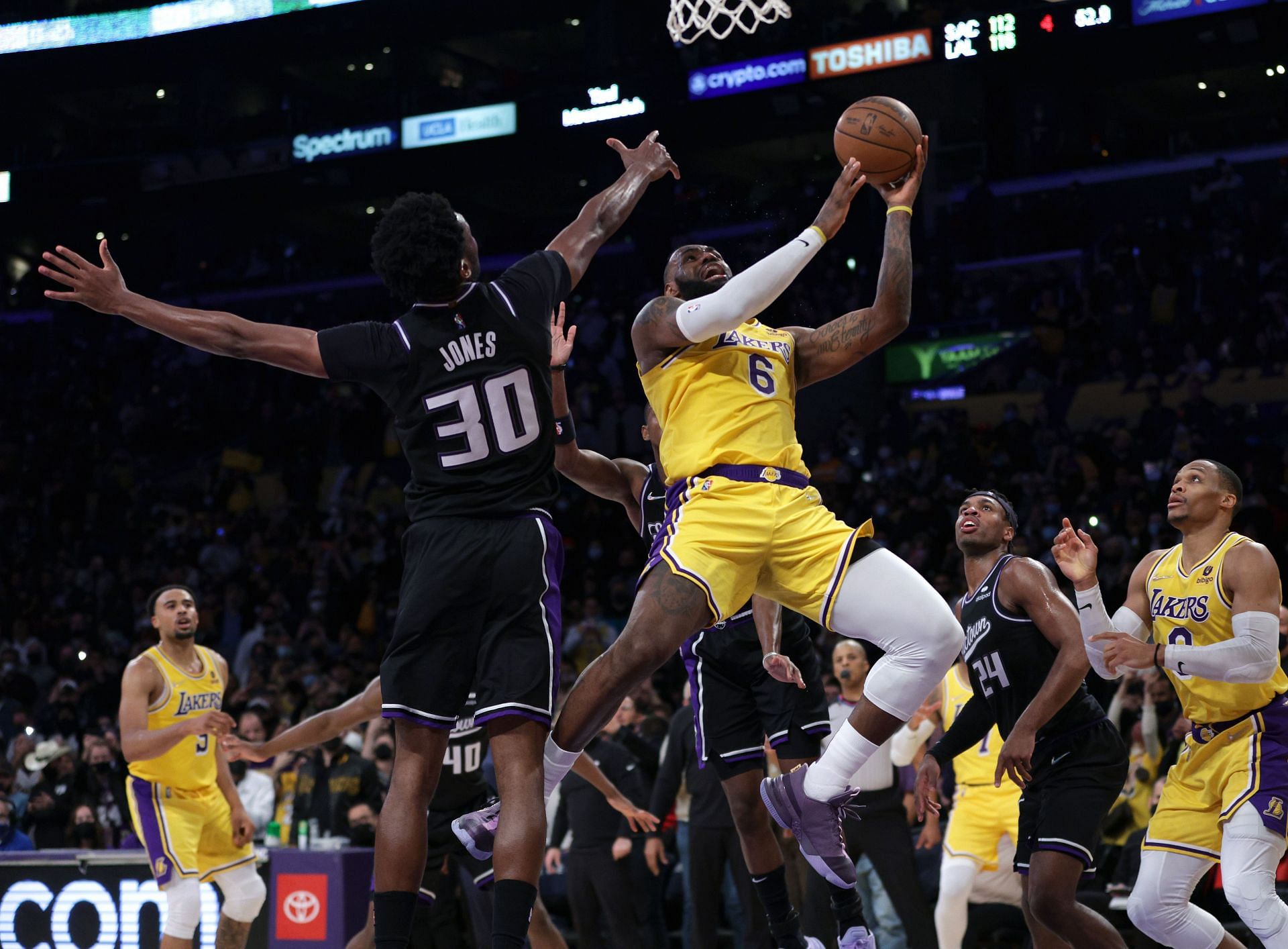 LeBron James of the LA Lakers scores as he is fouled in front of Damian Jones of the Sacramento Kings