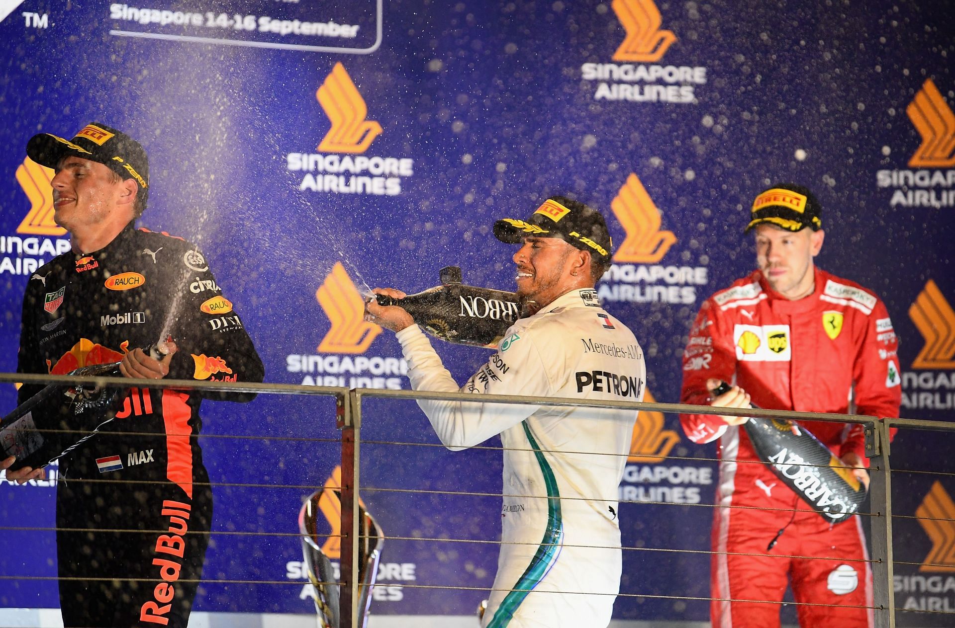 Max Verstappen (left), Lewis Hamilton (center), and Sebastian Vettel celebrate on the podium after the 2018 Singapore Grand Prix