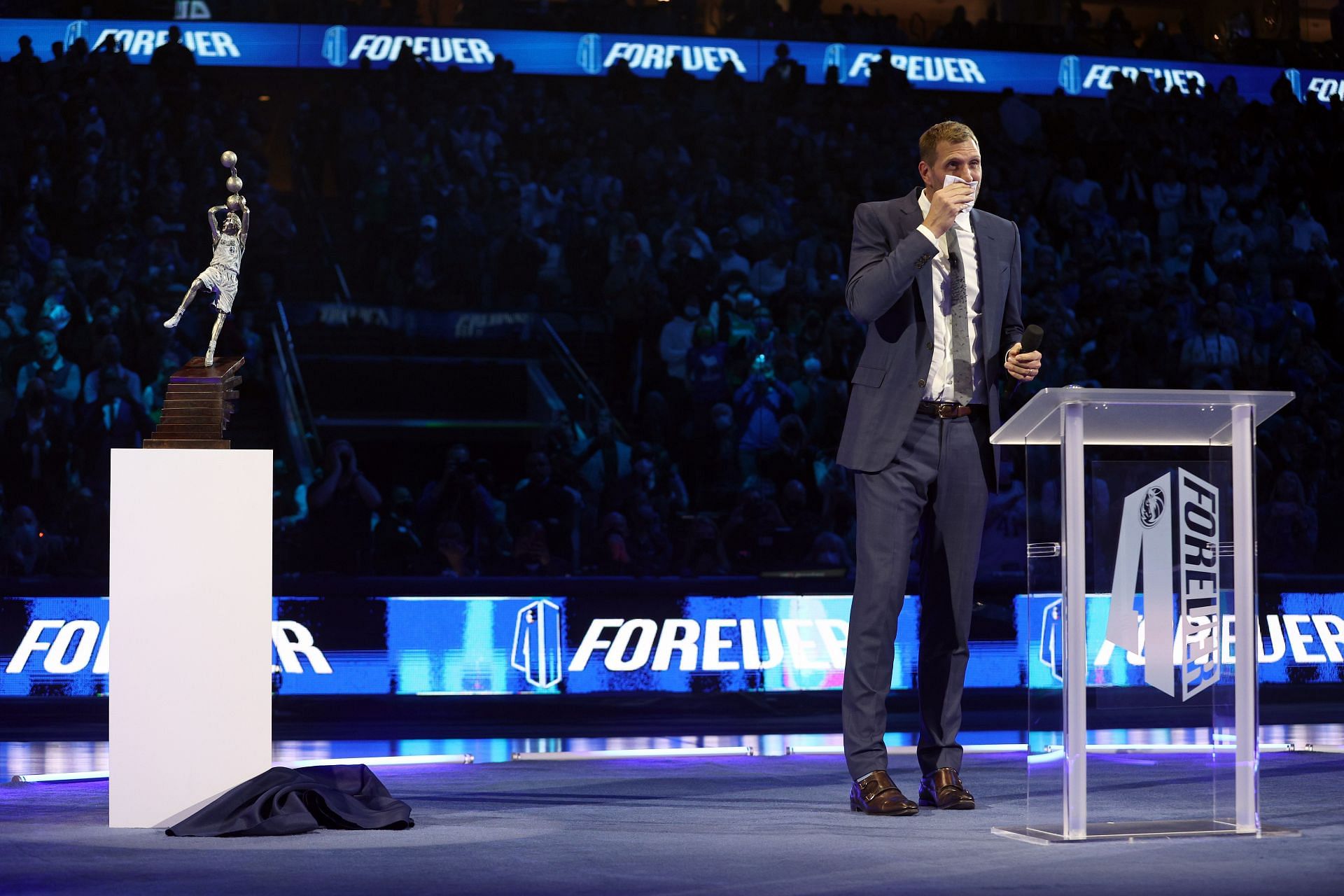 Dirk Nowitzki stands next to the model of his statue at his jersey retirement ceremony