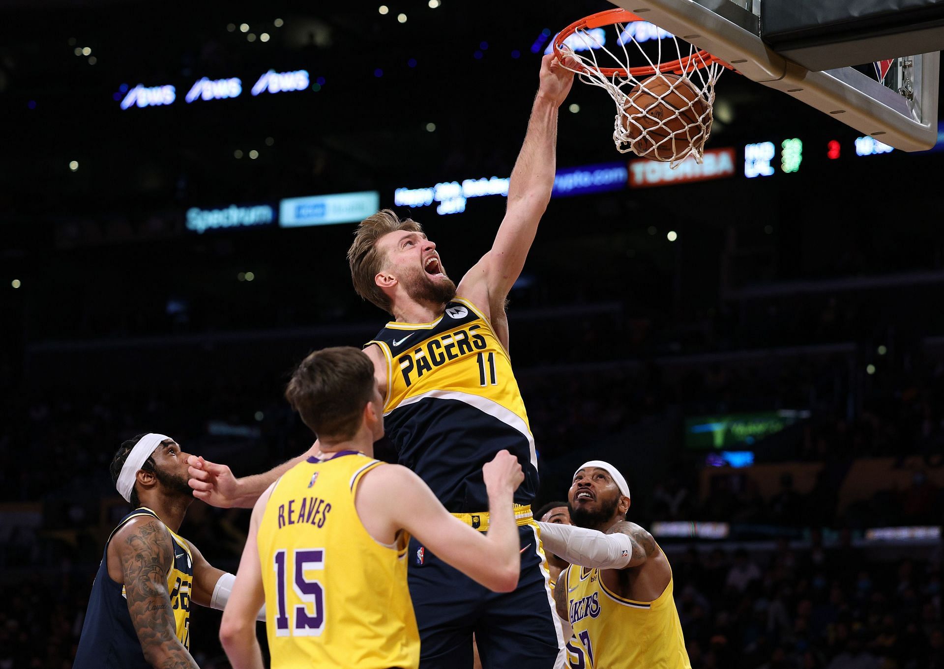 Domantas Sabonis of the Indiana Pacers dunks between Carmelo Anthony and Austin Reaves of the LA Lakers.