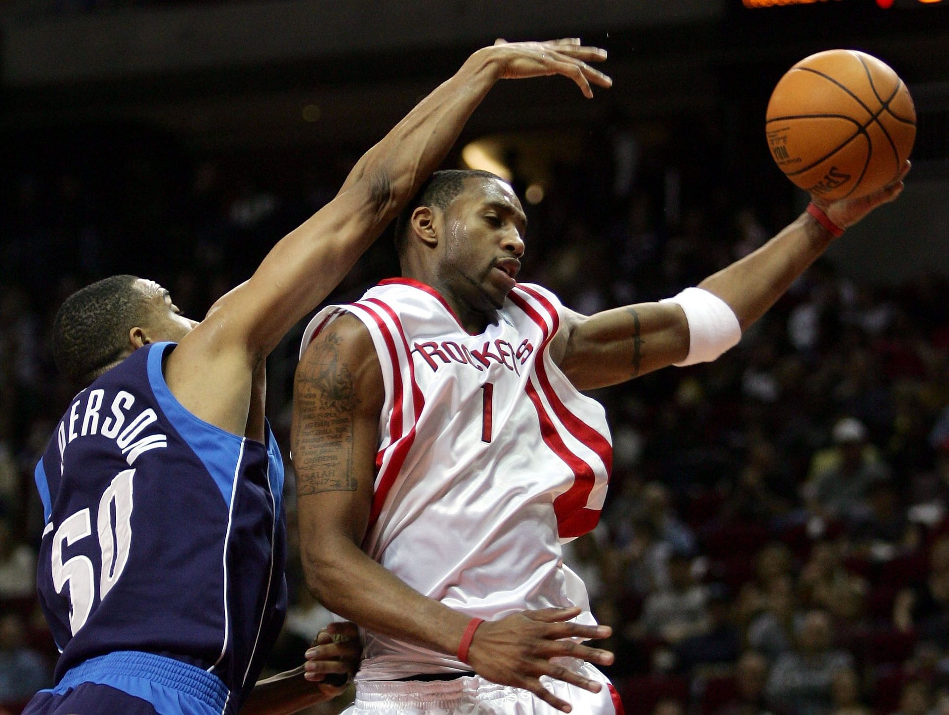 Tracy McGrady of the Houston Rockets takes a rebound away from Alan Henderson of the Dallas Mavericks.