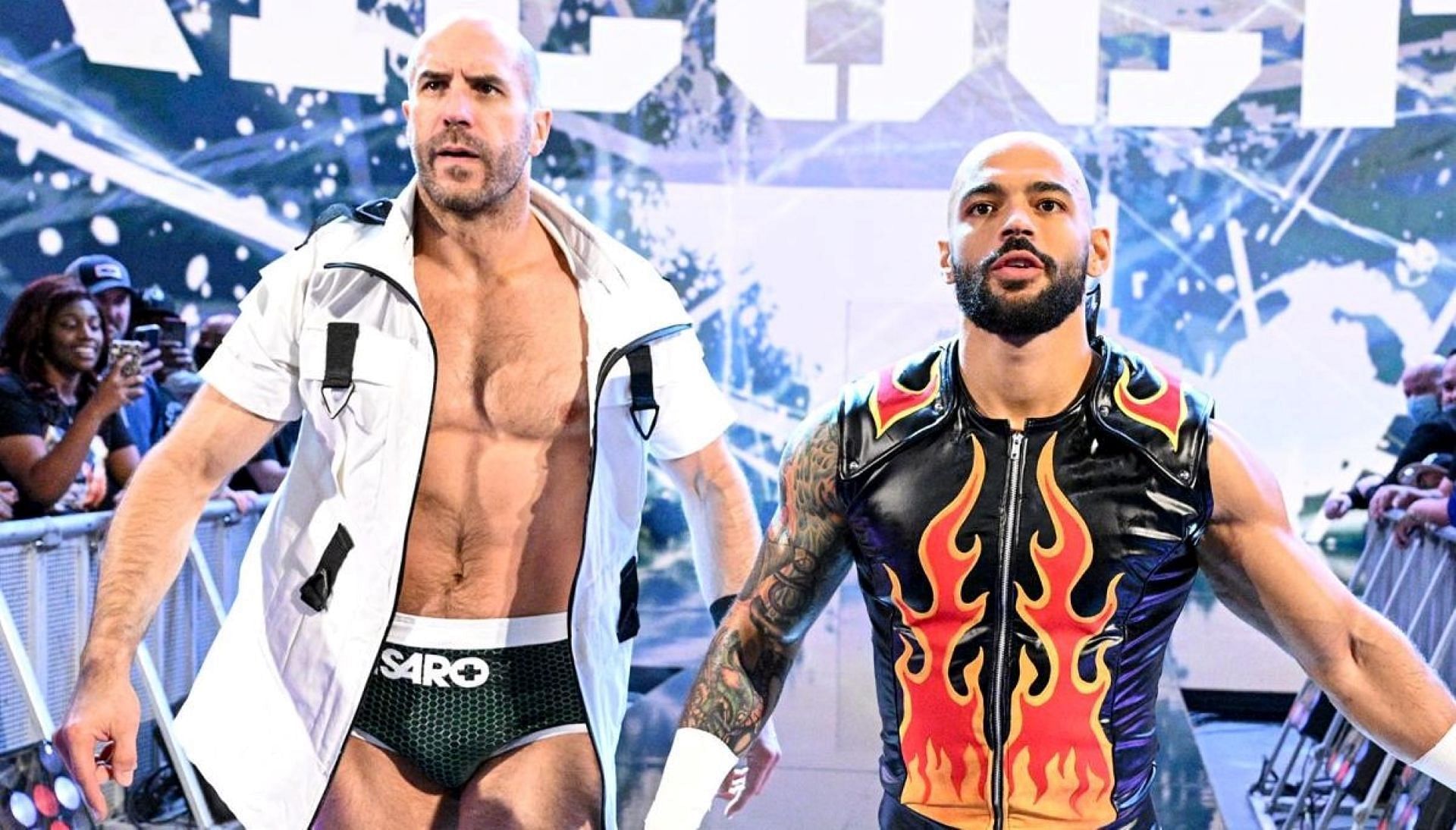 Cesaro walks down to the ring with Ricochet.
