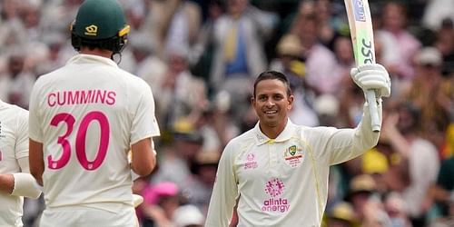 Khawaja celebrates his century as Cummins looks on.