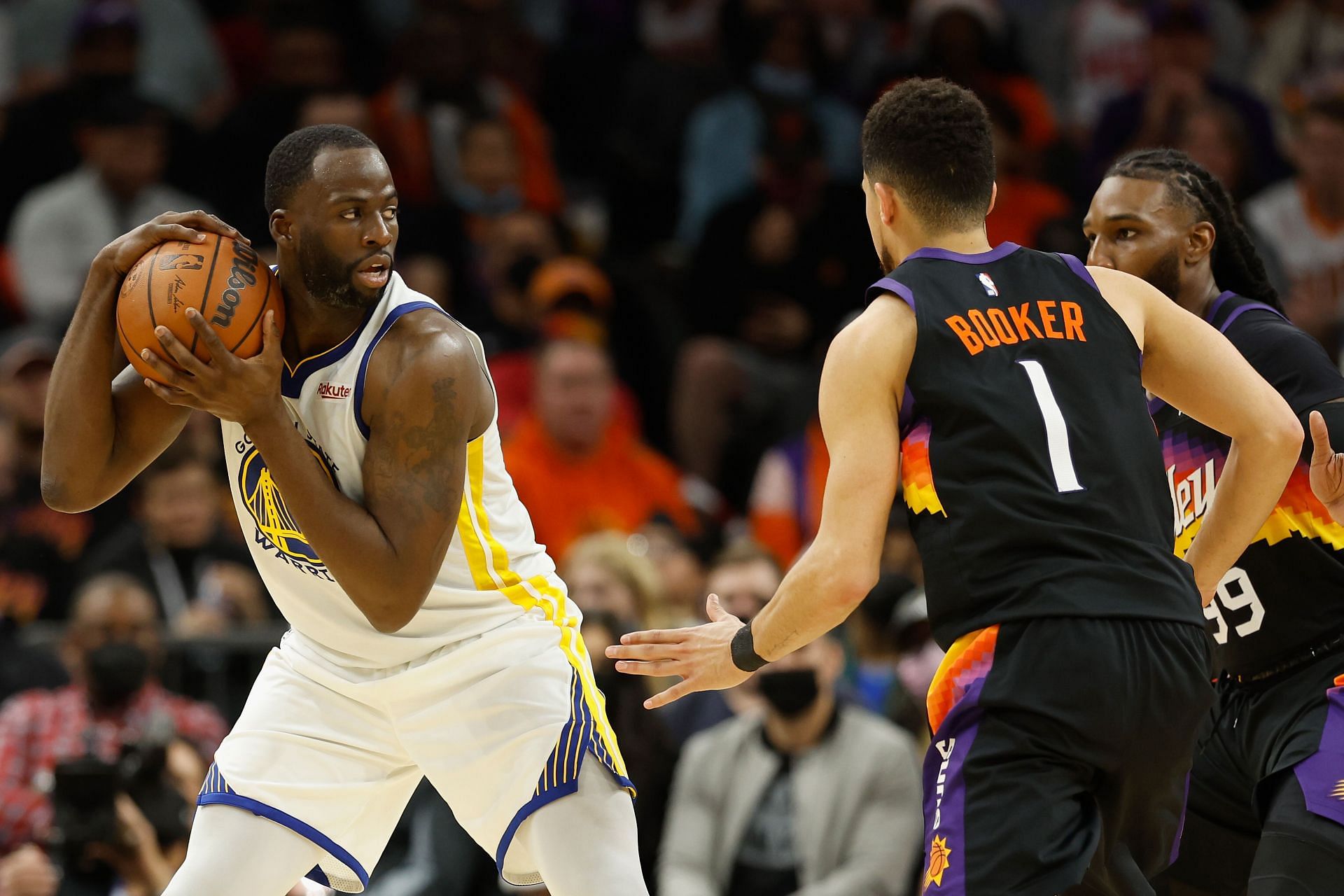 Draymond Green of the Golden State Warriors handles the ball against Devin Booker of the Phoenix Suns on December 25 in Phoenix, Arizona.