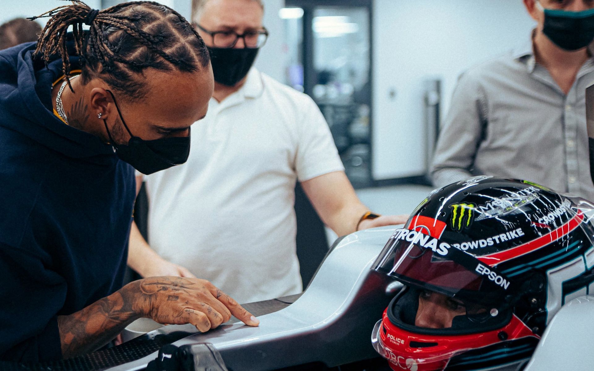 Lewis Hamilton (left) checks up on George Russell (bottom right) during the latter&#039;s seat fitting (Image Courtesy: Twitter/@MercedesAMGF1)