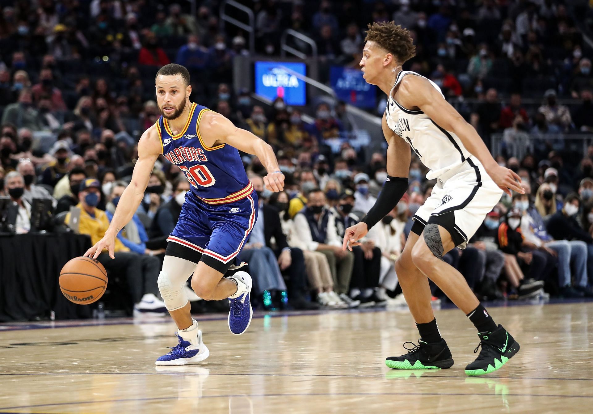 Steph Curry of the Golden State Warriors drives to the basket against Kessler Edwards of the Brooklyn Nets.