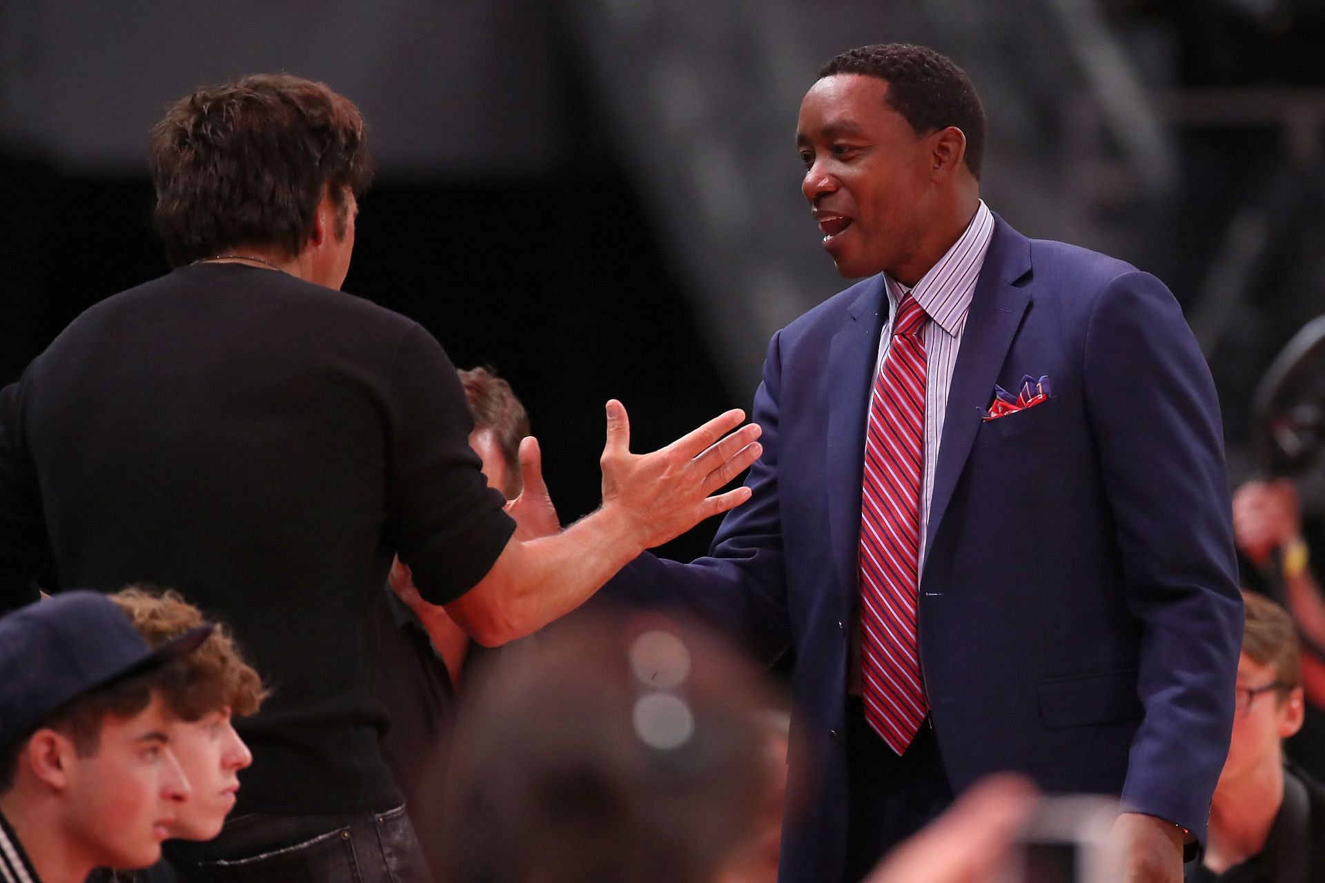 Former Detroit Piston Isiah Thomas talks with team owner Tom Gores prior to playing the Brooklyn Nets at the home opener at Little Caesars Arena on October 17, 2018 in Detroit, Michigan.