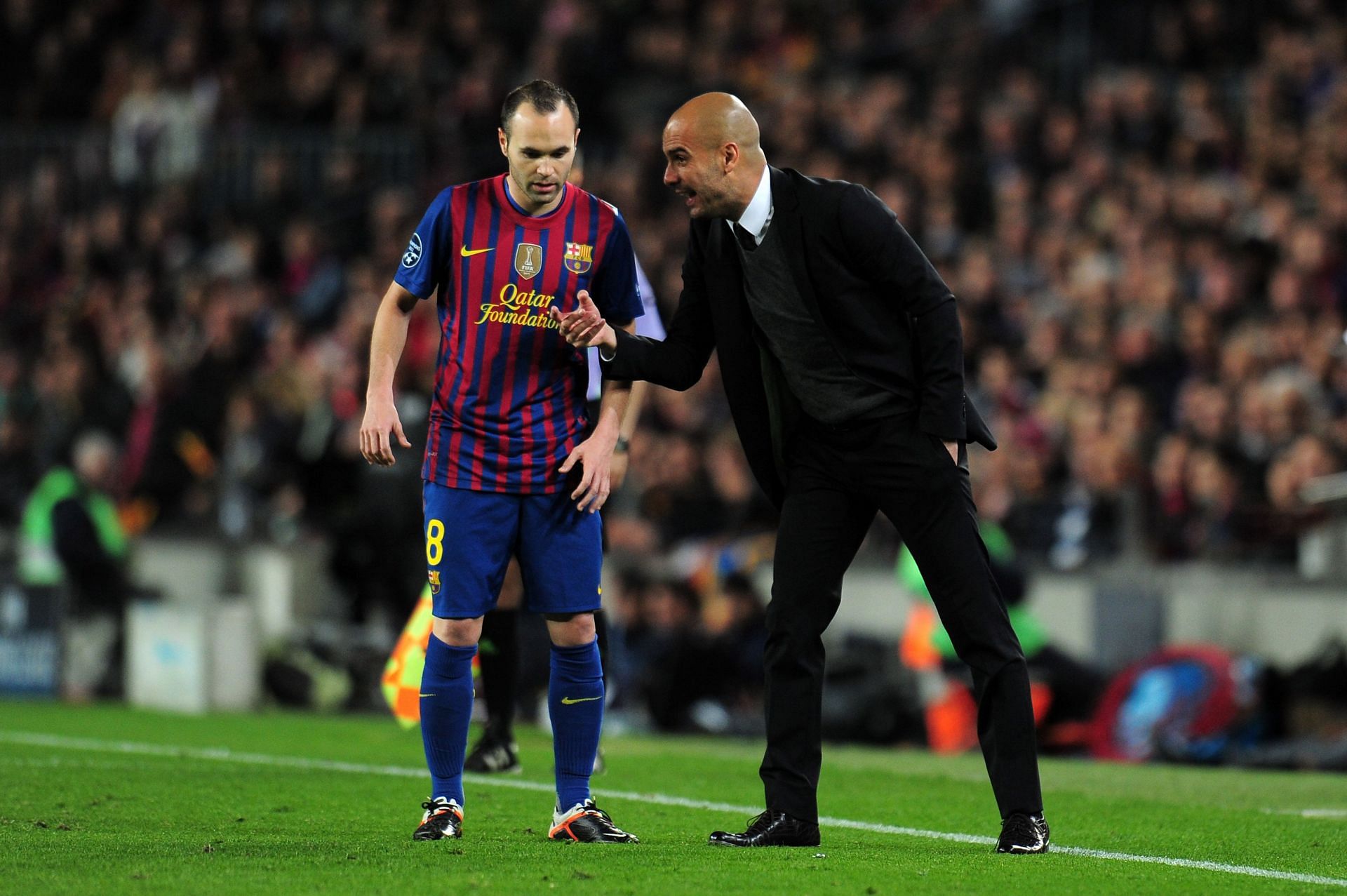 Andres Iniesta (left) gets instructions from Pep Guardiola on the Camp Nou touchline.