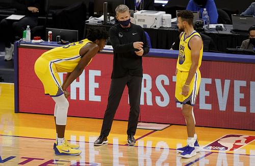 James Wiseman and Steph Curry talk to coach Steve Kerr during a timeout.