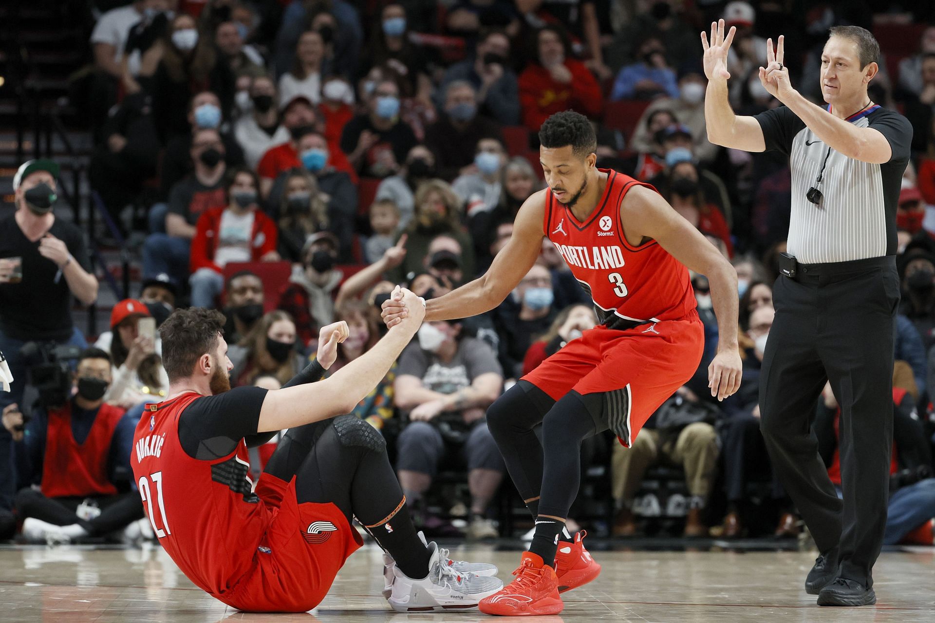 Jusuf Nurkic is helped up by his teammate CJ McCollum of the Portland Trail Blazers