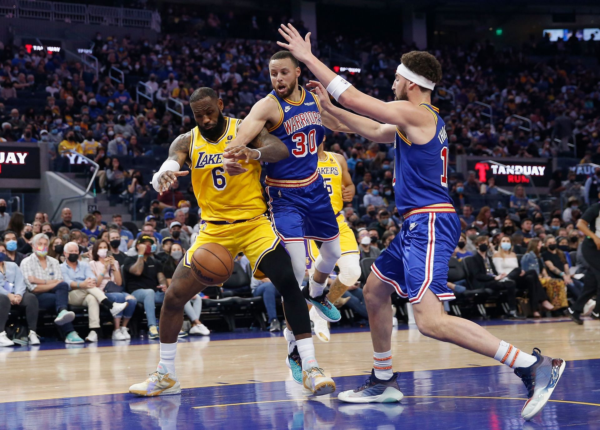 LeBron James #6 of the Los Angeles Lakers looks to gather a loose ball against Stephen Curry #30 and Klay Thompson #11 of the Golden State Warriors