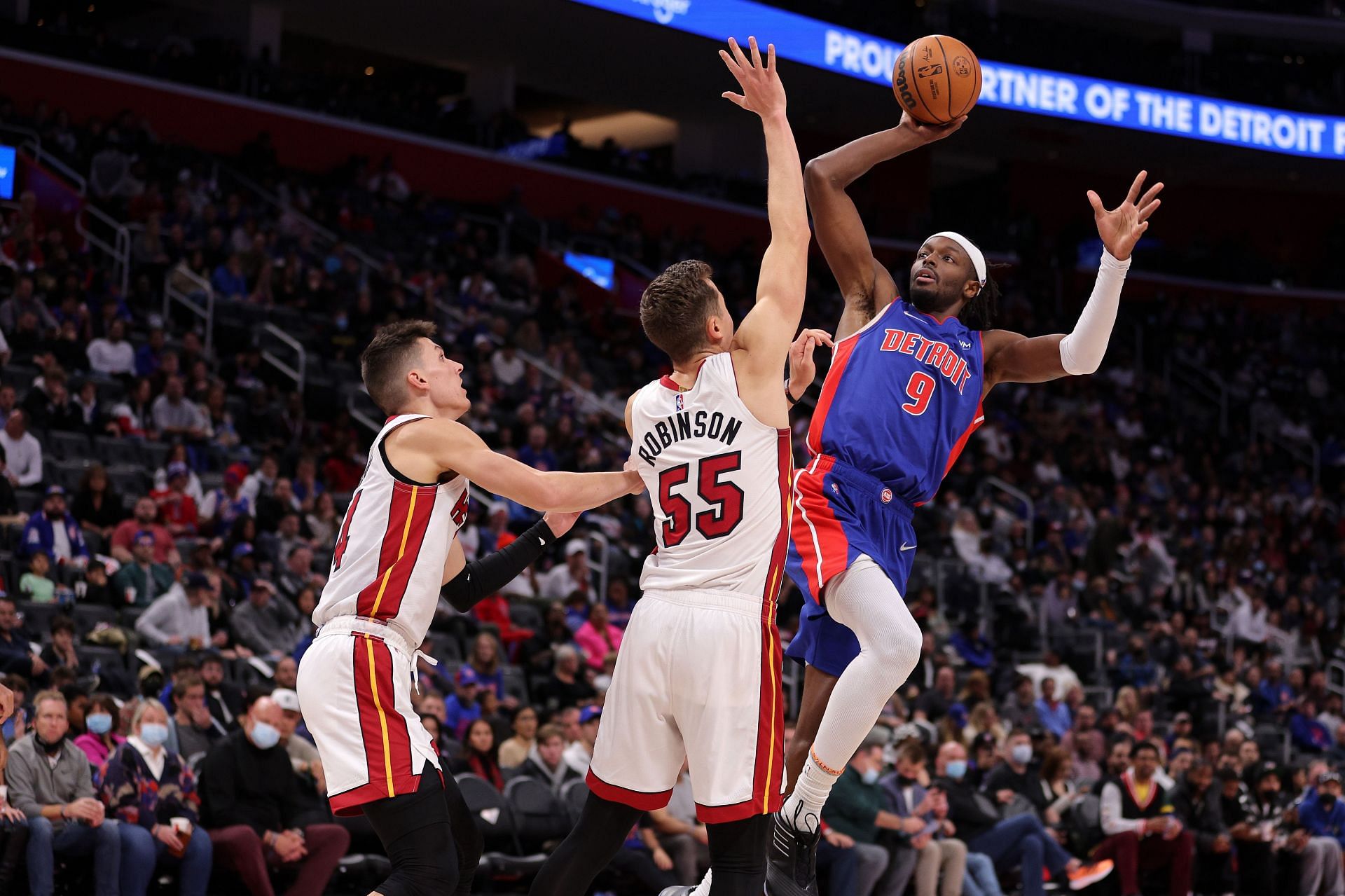Jerami Grant #9 of the Detroit Pistons tries to get a shot off over Duncan Robinson #55 and Tyler Herro #14 of the Miami Heat