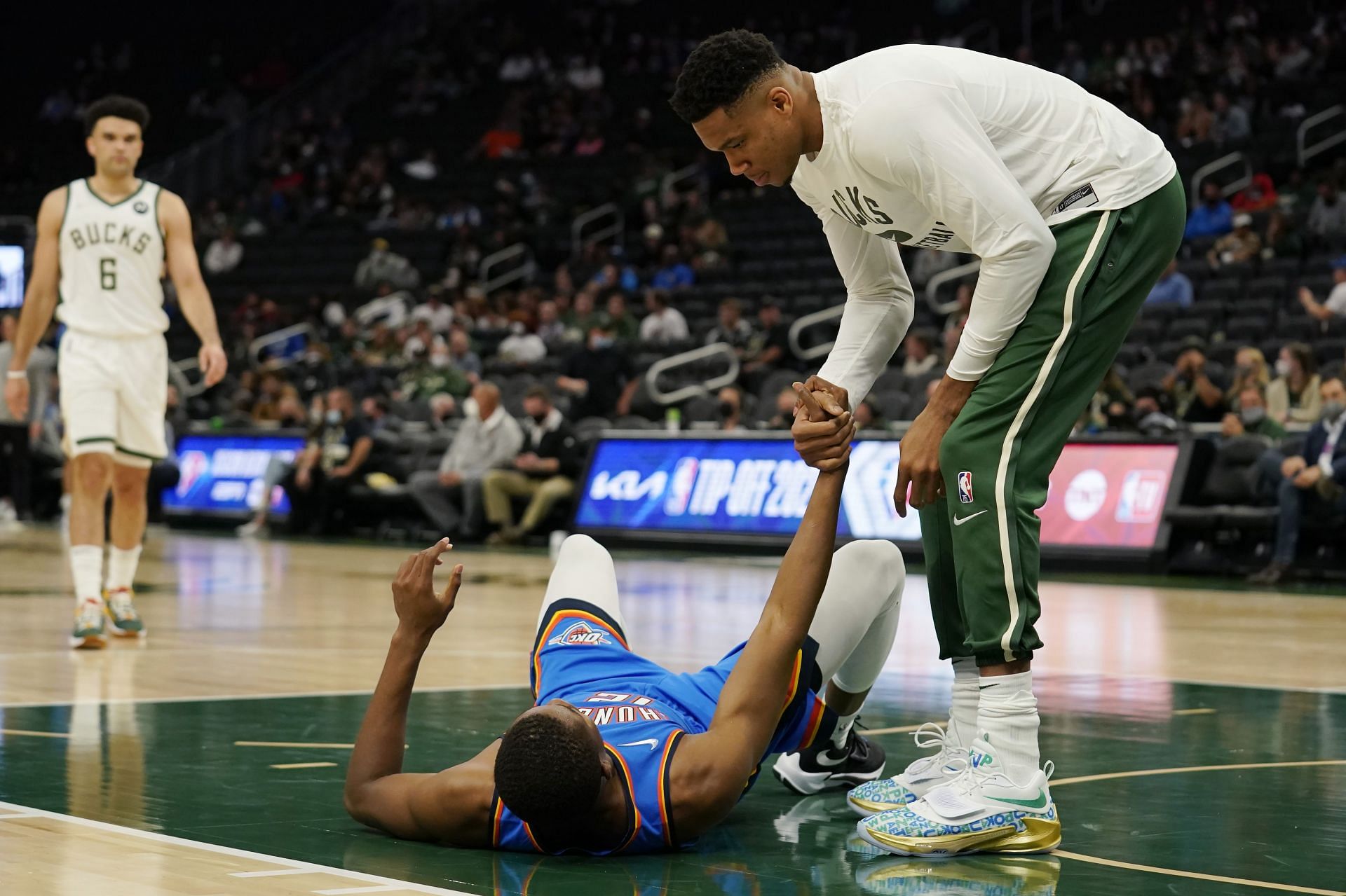 Giannis Antetokounmpo of the Milwaukee Bucks helps Mamadi Diakite of the OKC Thunder