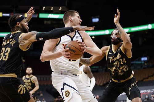 Toronto Raptors try to guard Nikola Jokic (C) of the Denver Nuggets.