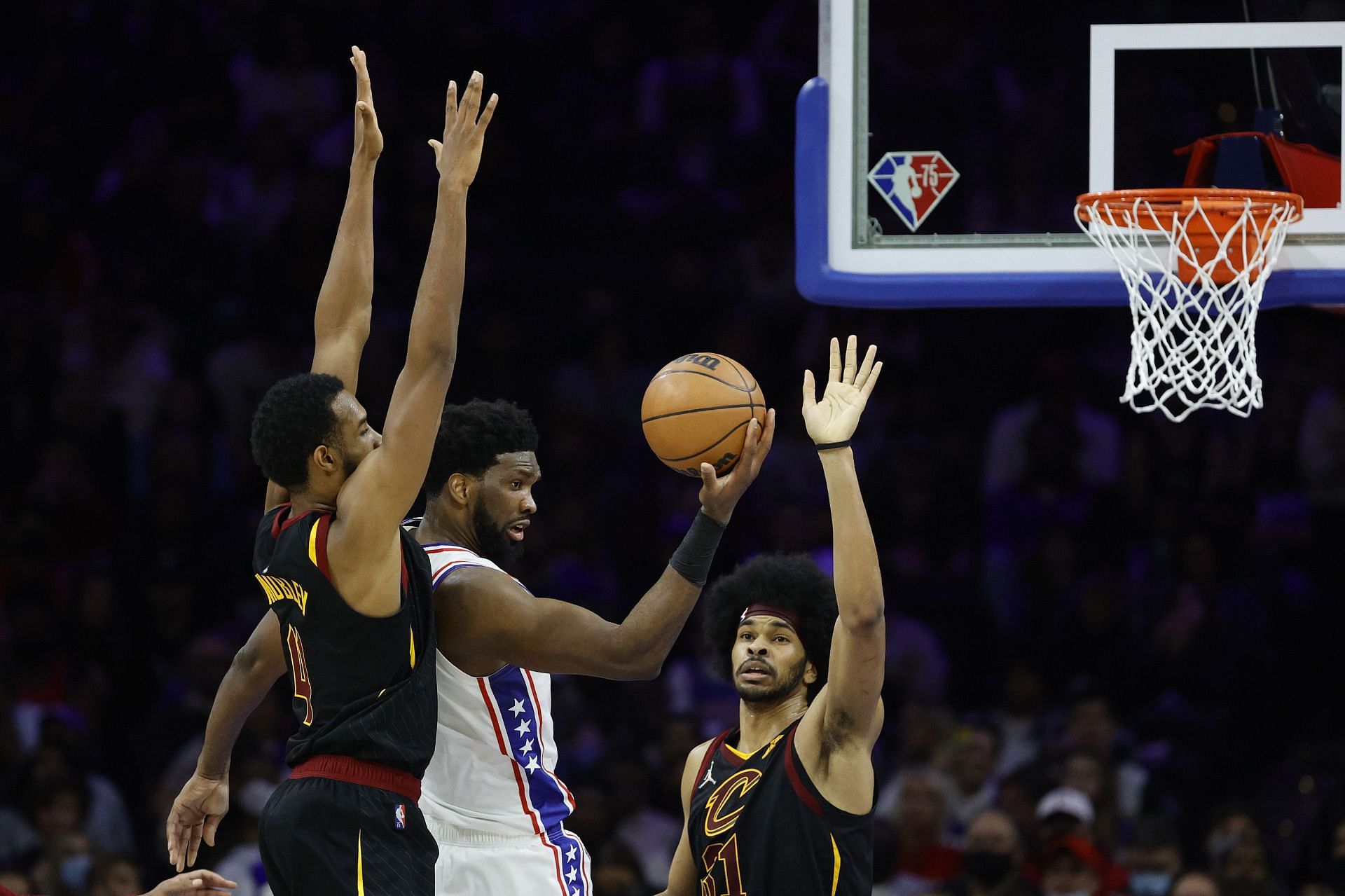 Joel Embiid #21 of the Philadelphia 76ers looks to pass between Evan Mobley #4 and Jarrett Allen #31 of the Cleveland Cavaliers at Wells Fargo Center on February 12