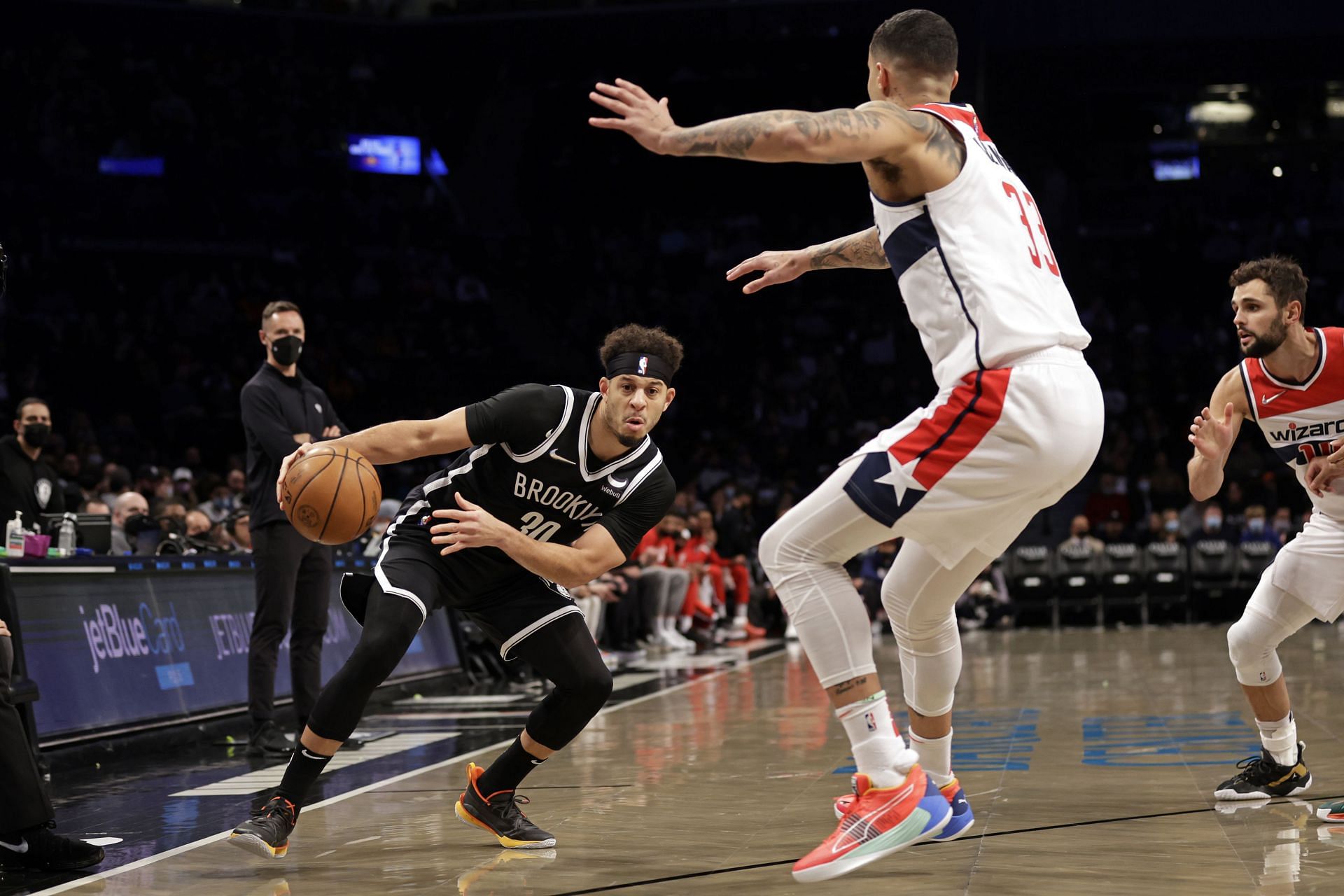 Seth Curry #30 of the Brooklyn Nets drives past Kyle Kuzma #33 of the Washington Wizards during the first half at Barclays Center on February 17, 2022 in New York City