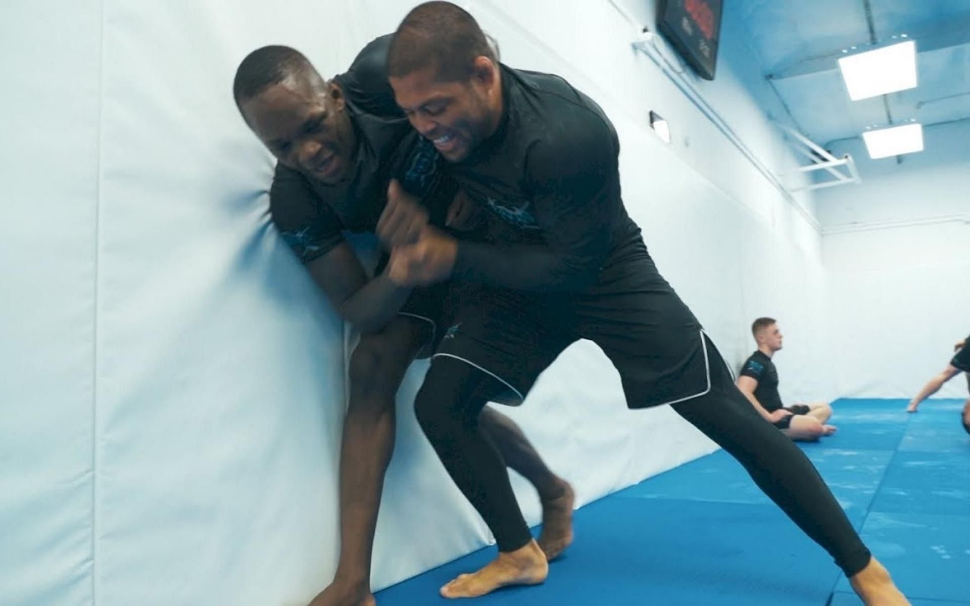 Israel Adesanya (left) trains grappling with Andre Galvao (right). Galvao takes on Reinier de Ridder in a grappling match at ONE X. [Image courtesy of FloGrappling&#039;s YouTube page]