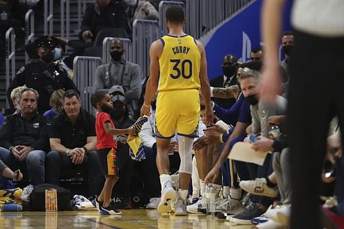 Draymond Jr. and Steph Curry on the sidelines during a game [Source MLive.com]