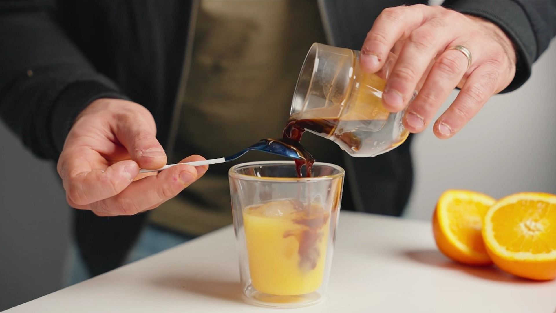 Pour the cold brew concentrate over a spoon instead of directly into the juice (Image via Kyle Rowsell/YouTube)