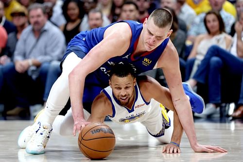 Nikola Jokic of the Denver Nuggets fights for a loose ball against Steph Curry of the Golden State Warriors