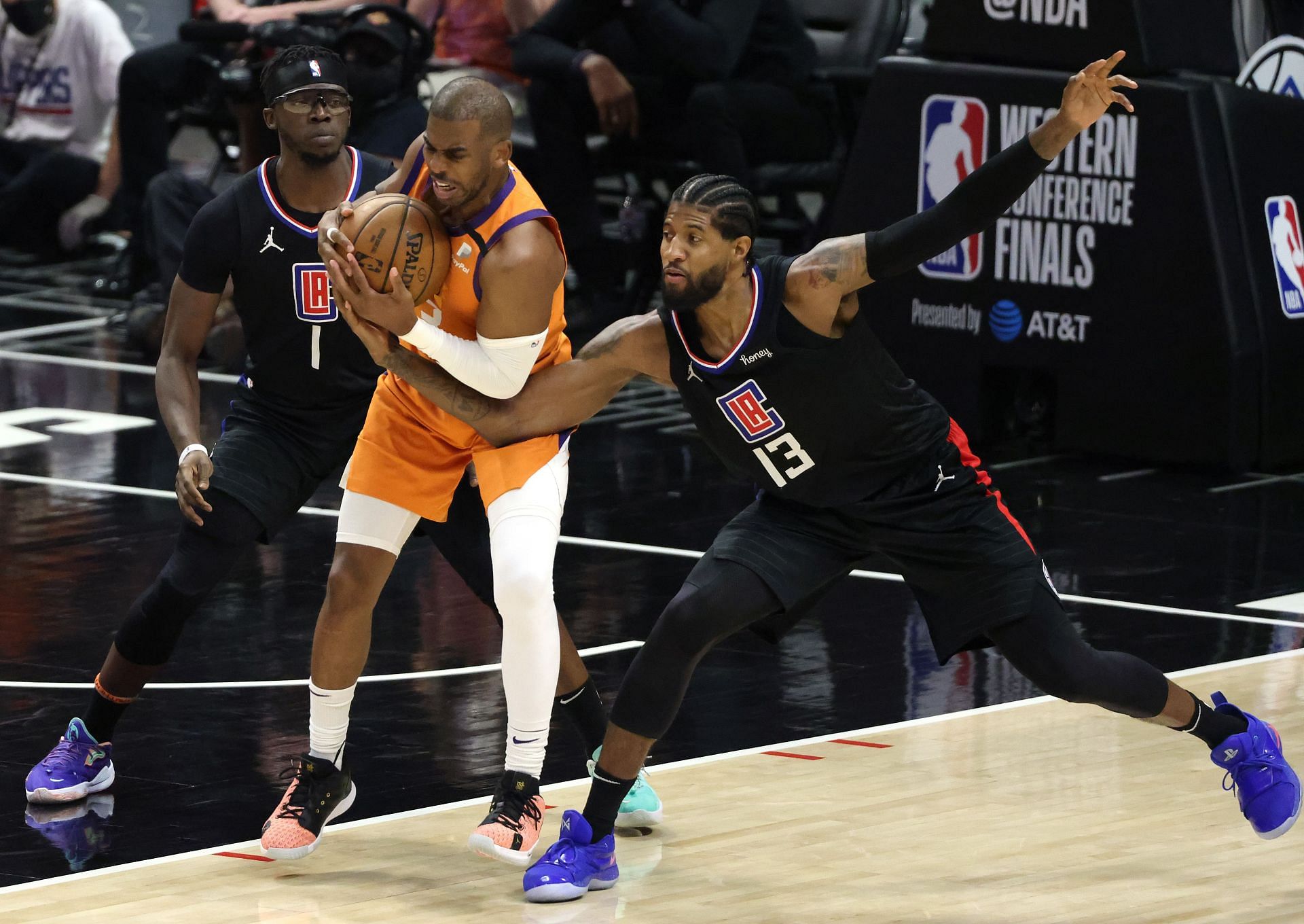 Chris Paul of the Phoenix Suns protects the ball against Reggie Jackson and Paul George of the LA Clippers