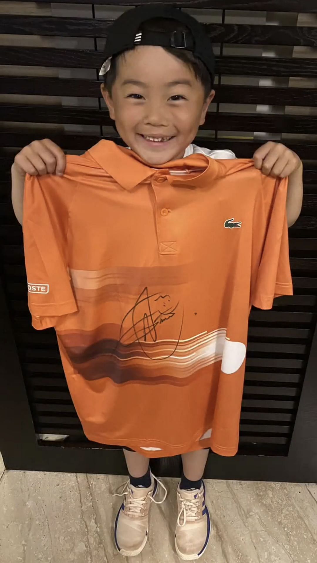 Kojiro Owaki holds an autographed shirt from Novak Djokovic.