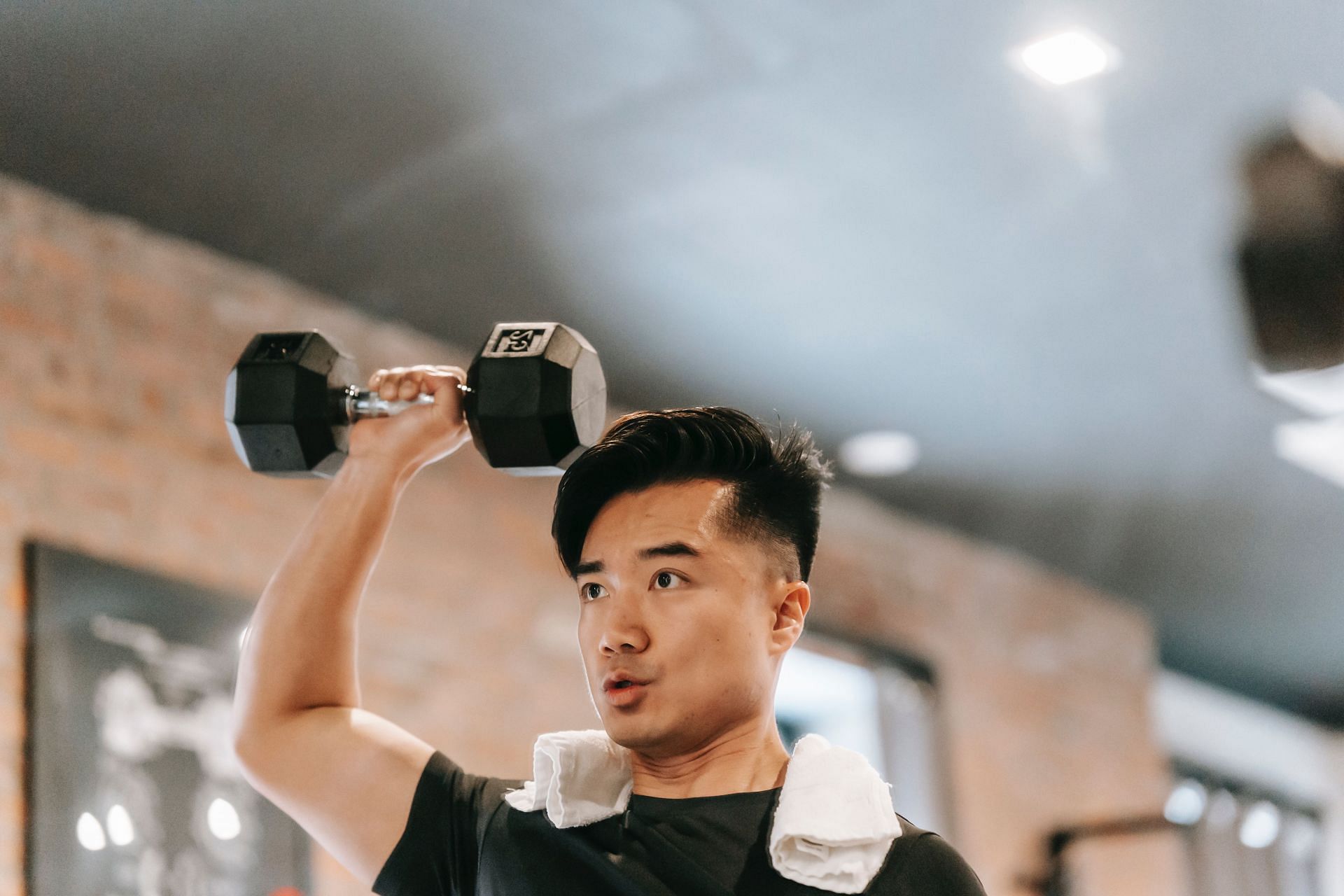 Overhead dumbbell press for shoulder strength (Image via Pexels/Andres Ayrton)