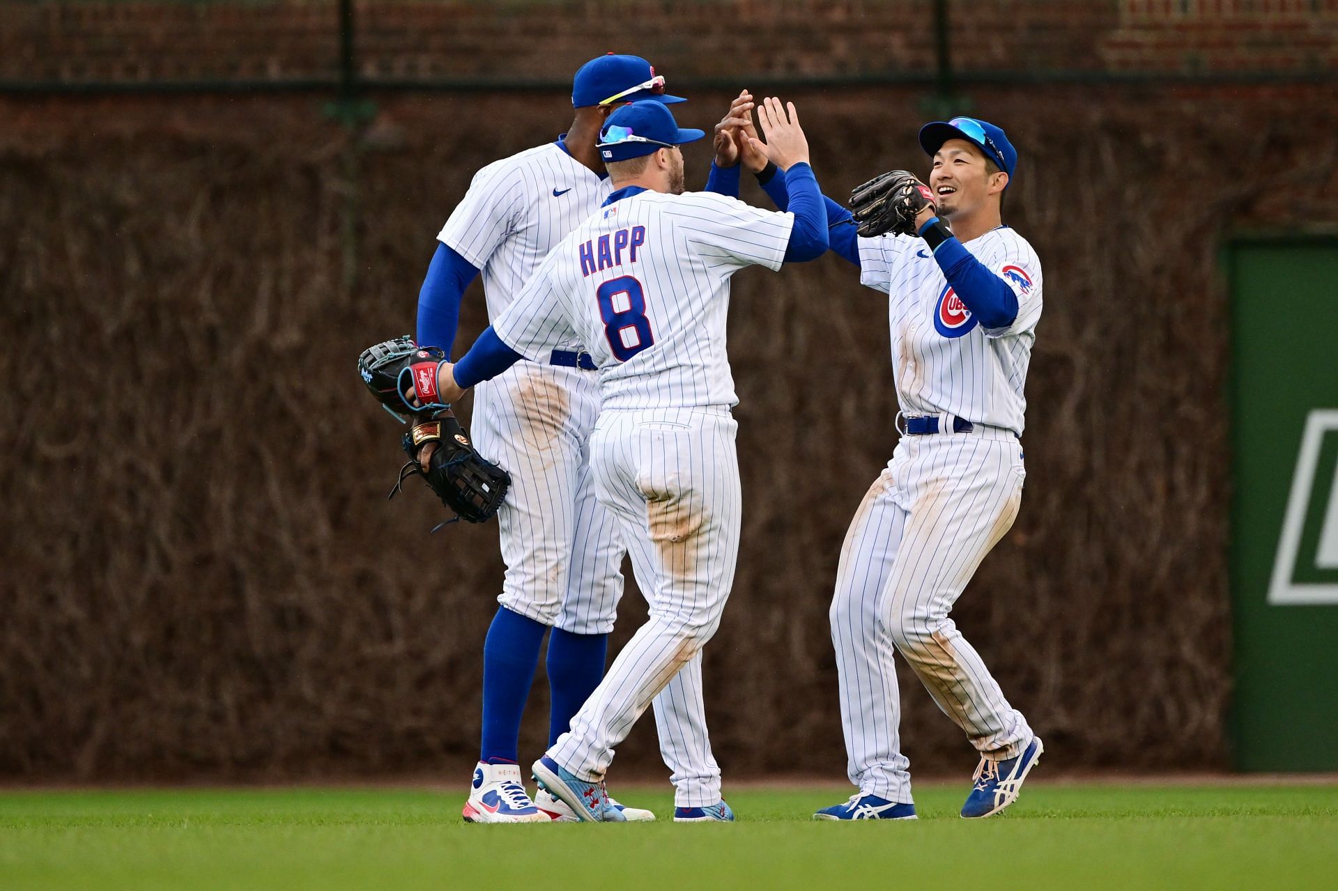 Ian Happ (center), Jason Heyward (left), and Seiya Suzuki (right) celebrate after an Opening Day victory against the Milwaukee Brewers.