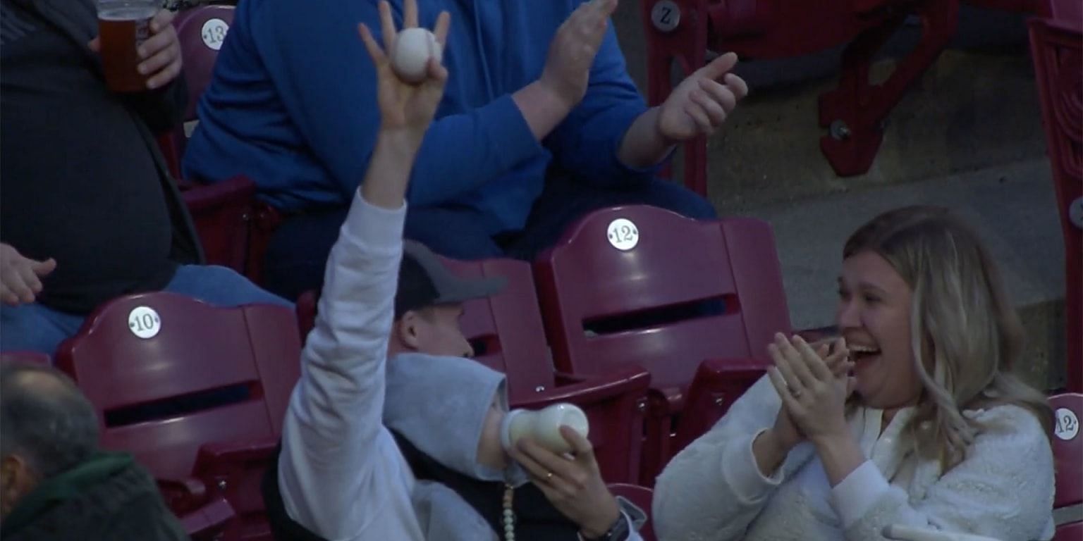 A fan at the Cincinnati Reds vs. Padres game makes a spectacular catch while holding a baby.