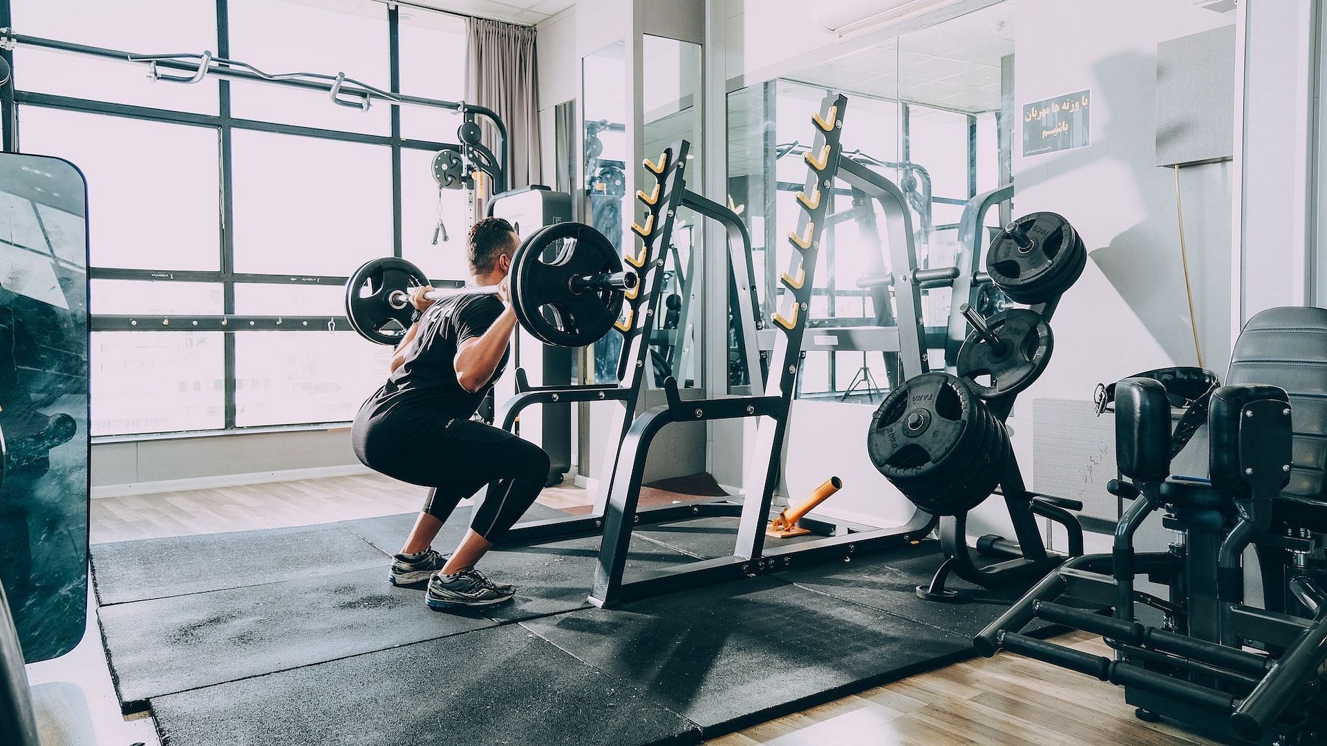 Man performing barbell squat. Image via Unsplash/Sam Moqadam