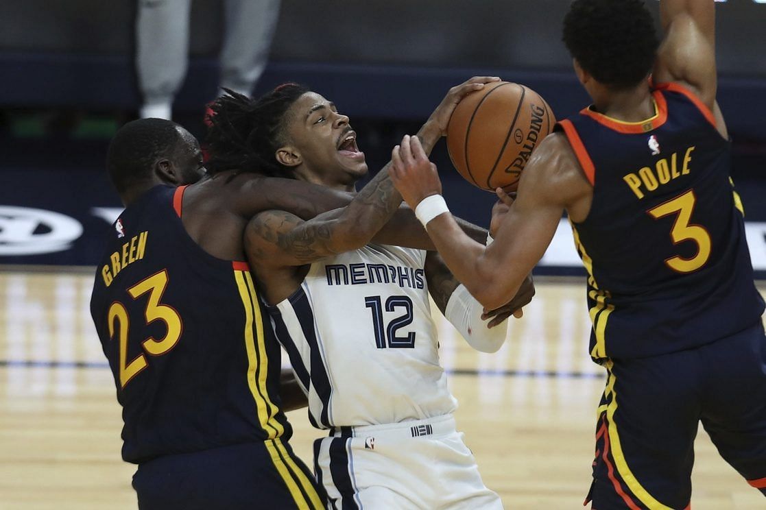 Draymond Green and Jordan Poole of the Golden State Warriors defend Ja Morant of the Memphis Grizzlies.