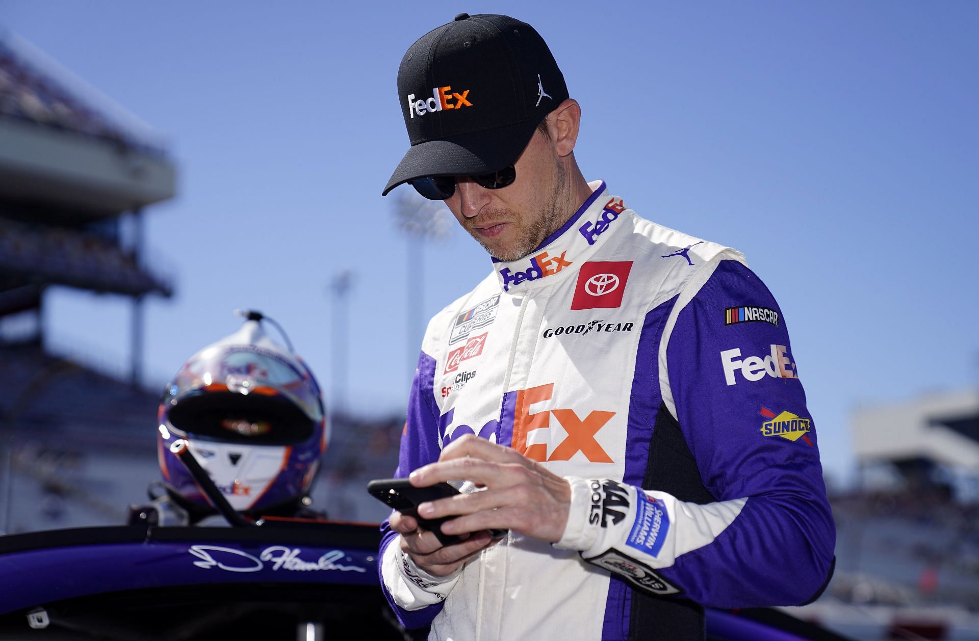Denny Hamlin uses his cell phone on the grid during qualifying for the NASCAR Cup Series Toyota Owners 400 at Richmond Raceway.