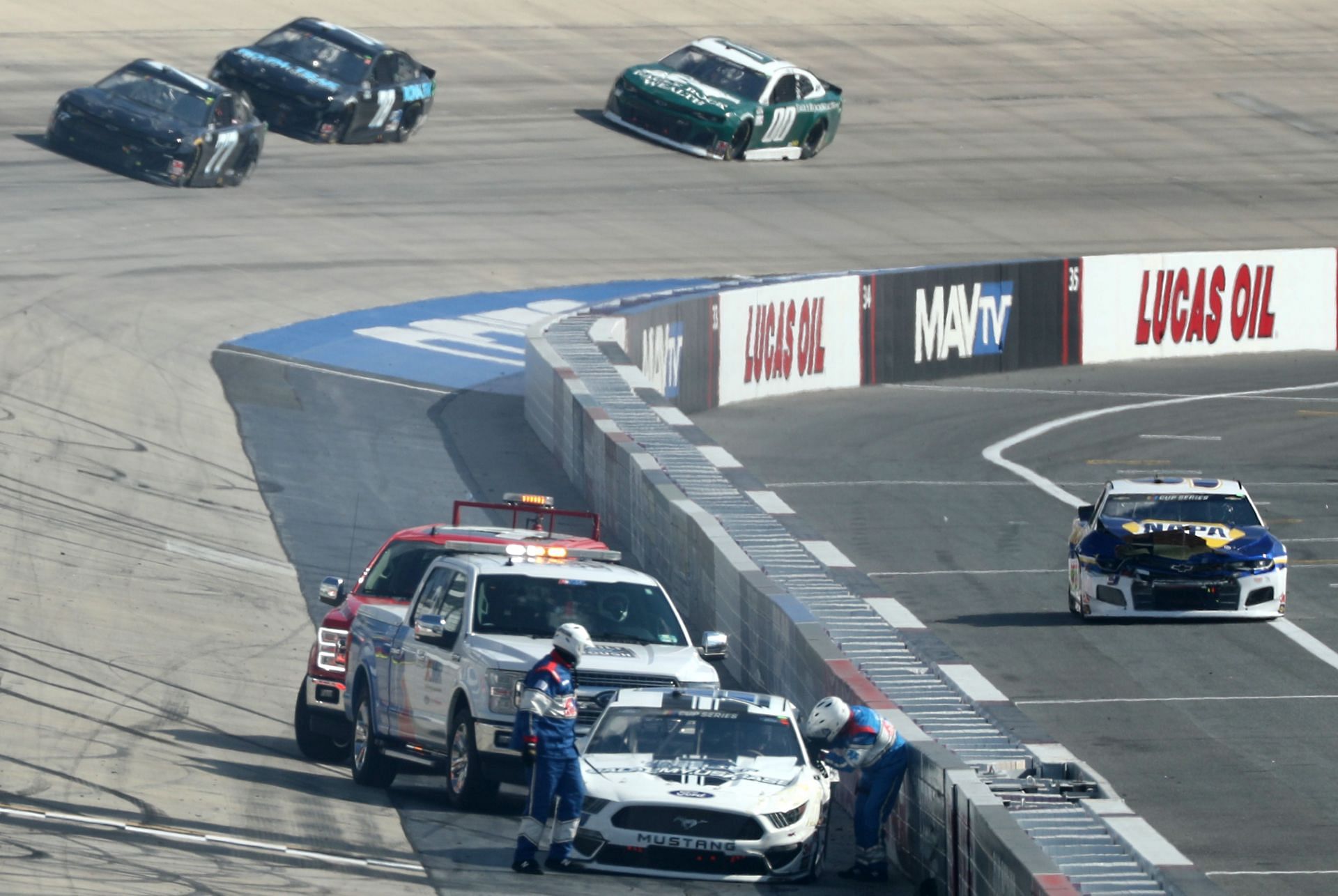 The safety crew attend to Joey Gase, driver of the #51 Ford, as Chase Elliott, driver of the #9 NAPA Auto Parts Chevrolet, leaves the track after an on-track incident during the NASCAR Cup Series Drydene 311 at Dover International Speedway (Photo by Hunter Martin/Getty Images