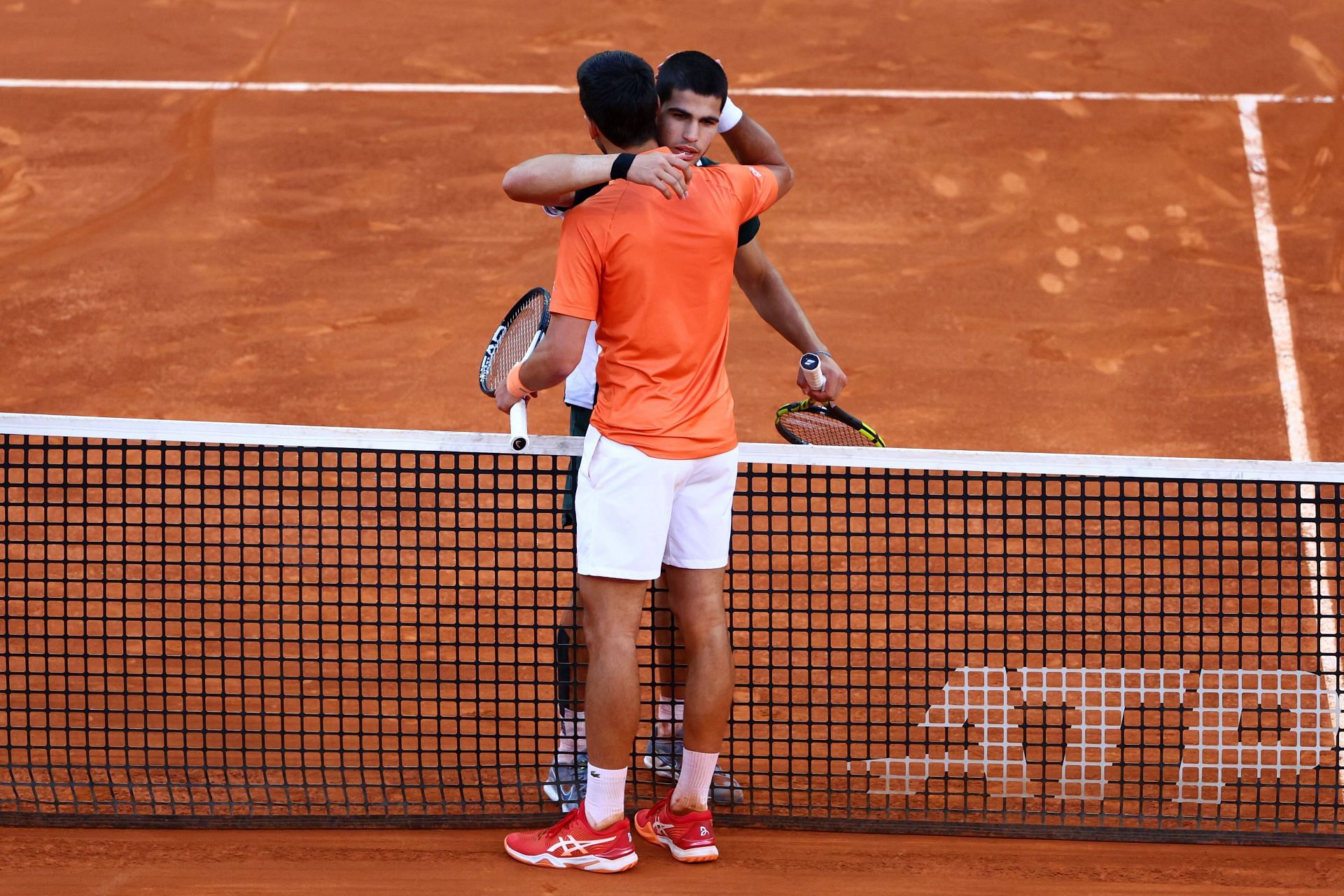 Carlos Alcaraz and Novak Djokovic hug after their semi-final encounter in Madrid