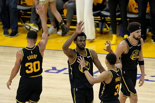 Andrew Wiggins celebrates a play with Steph Curry and Jordan Poole.