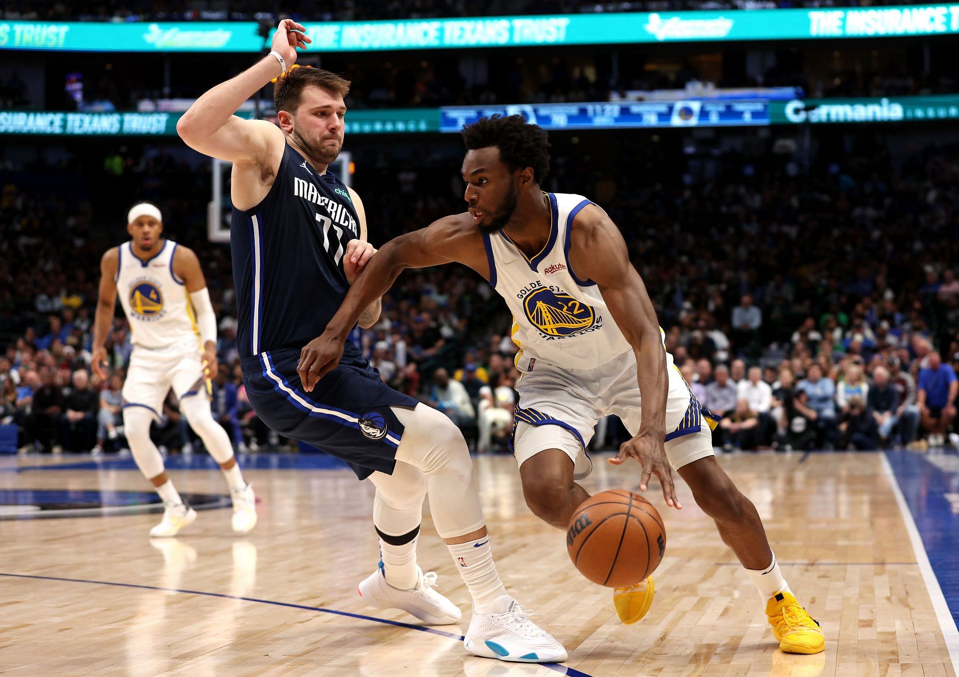 Andrew Wiggins #22 of the Golden State Warriors drives past Luka Doncic #77 of the Dallas Mavericks